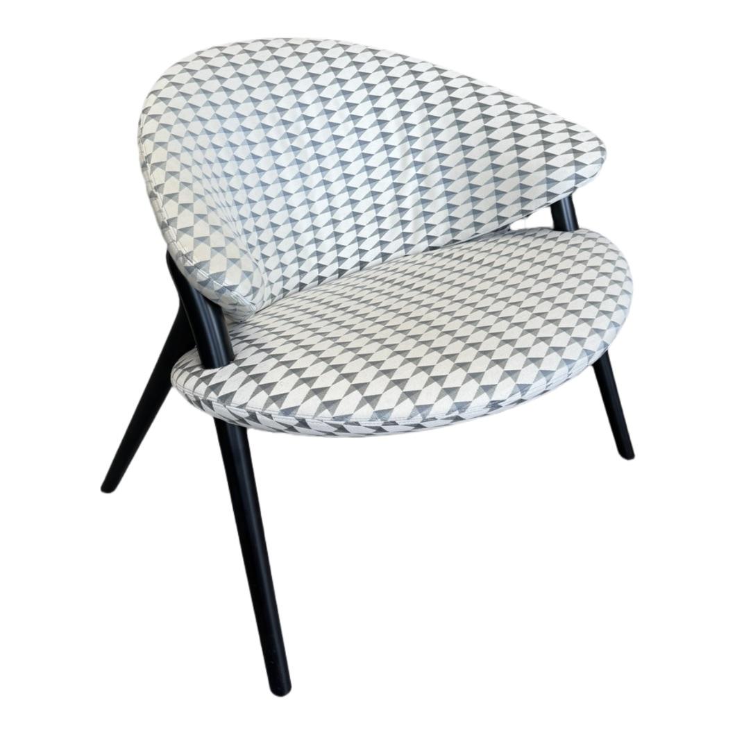 L'ensemble sculptural de l'assise danse sur la délicatesse des pieds.  Vu de face, le fauteuil évoque l'idée d'une coquille ouverte, incarnée par l'assise et le dossier moelleux, aux courbes enveloppantes et généreuses. Des éléments en polyuréthane