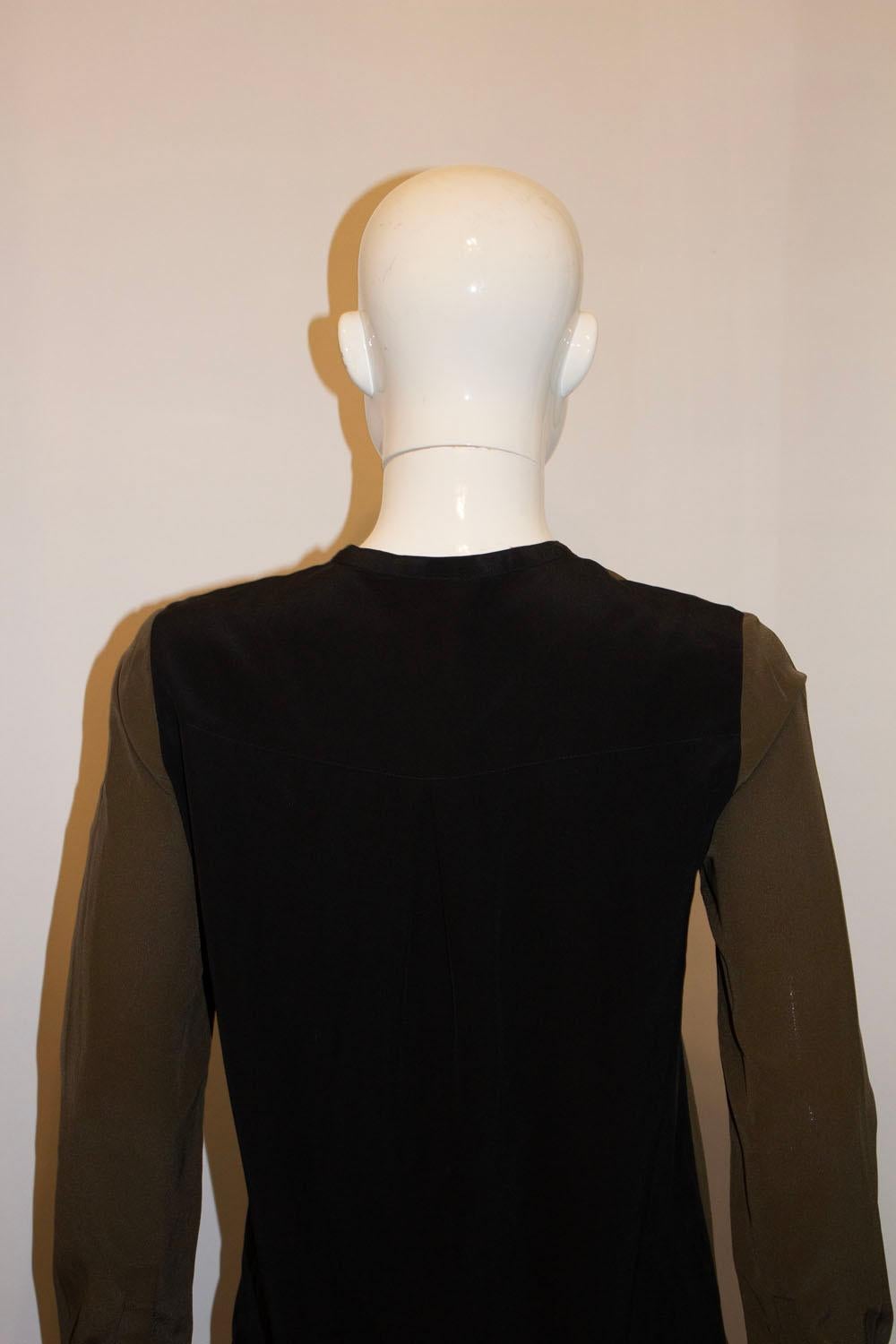 A wonderful two colour block silk top by Vince. In black and olive green colours , the top has a button front opening, with a fold at the front and vent at the back.  It has a two button cuff, and is unlined. 
Size 4, measurements: Bust 37'', length