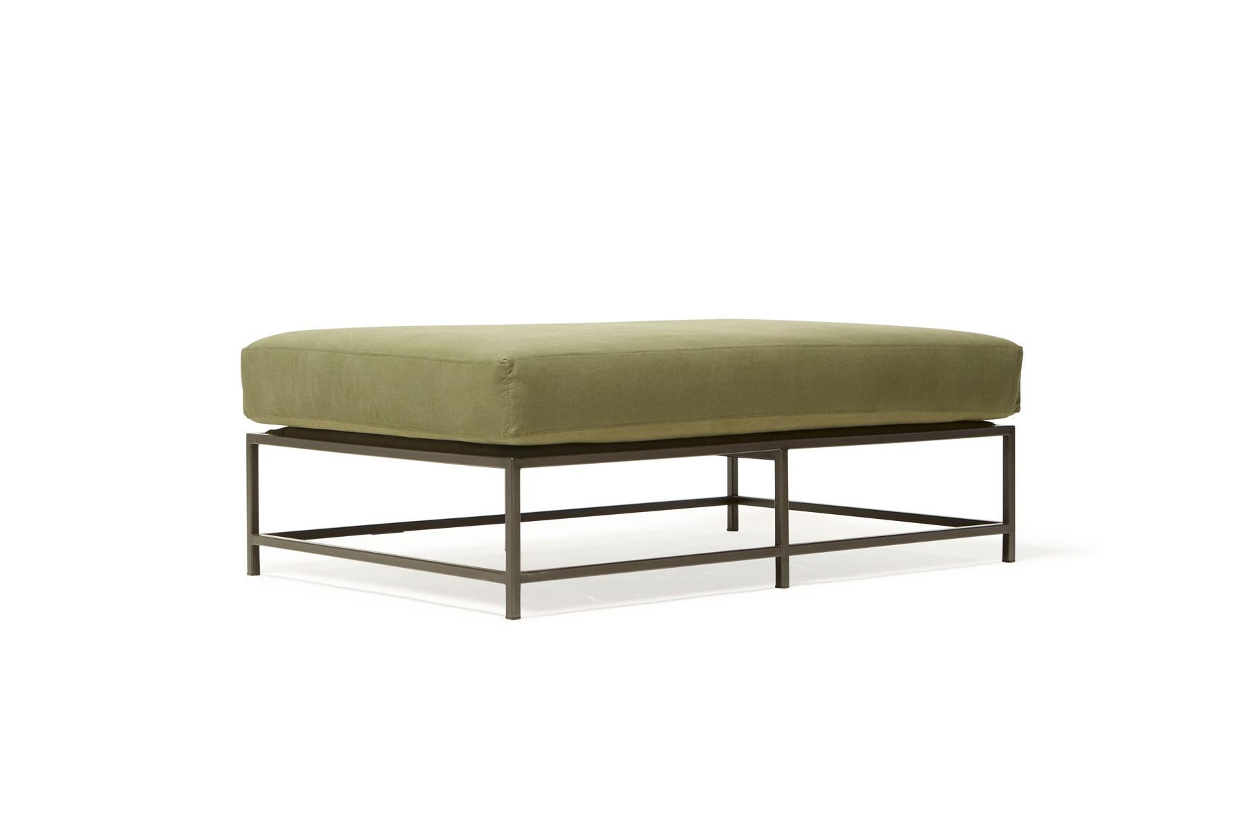 The Inheritance bench is a versatile piece that can be used as a chaise extension on any sofa, as an independent seating option or as a large upholstered coffee table. 

This variation is upholstered in olive canvas. Sitting atop a blackened steel