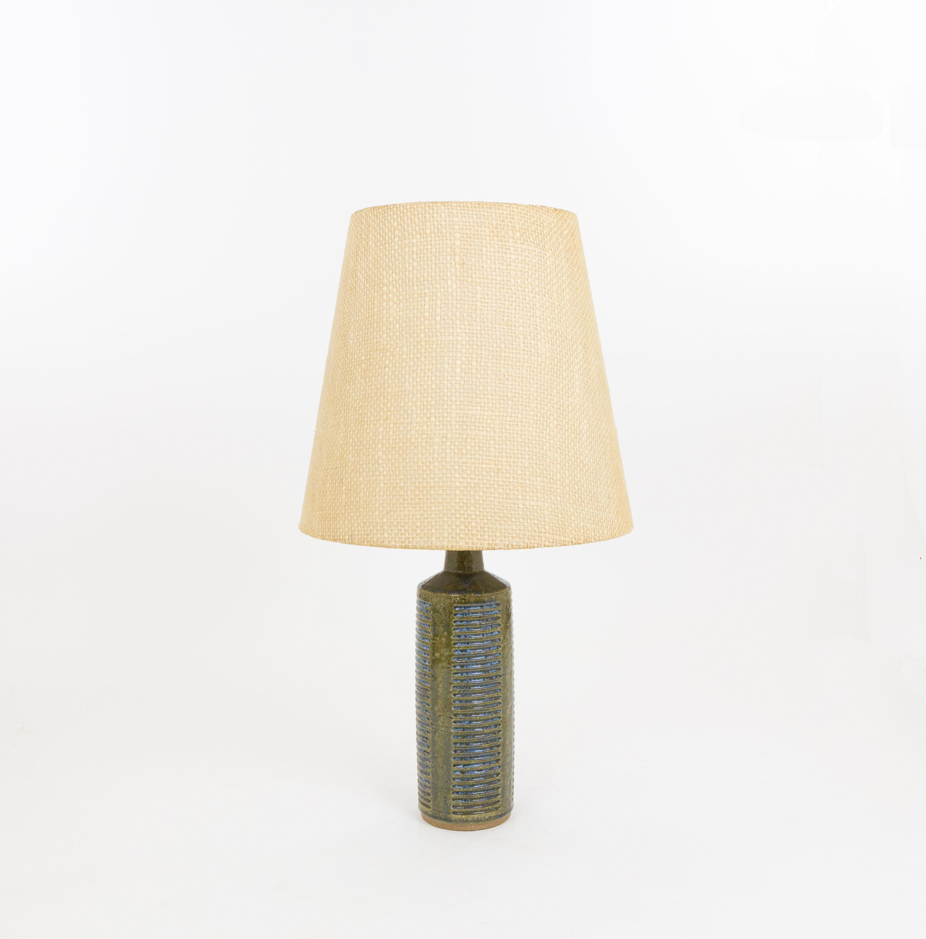 Lampe de table modèle DL/27 réalisée par Annelise et Per Linnemann-Schmidt pour Palshus dans les années 1960. La couleur de la base décorée à la main est vert olive et bleu. Il présente des motifs impressionnés.

La lampe est livrée avec son support
