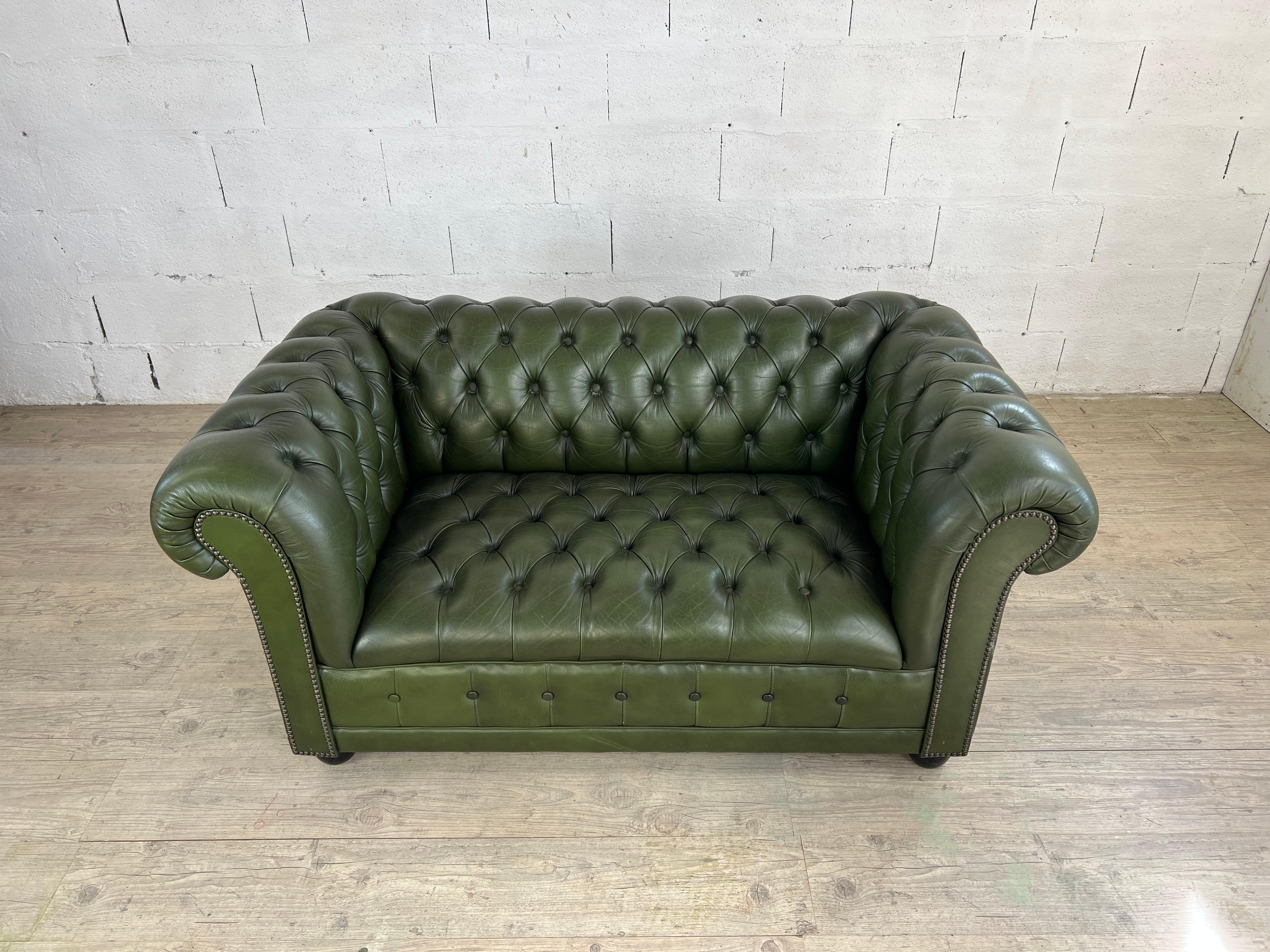 Elegante divano Chesterfield a due posti, realizzato con una struttura in legno massiccio e una profonda tappezzeria trapuntata a mano con la tradizionale tecnica dell'abbottonatura profonda, in cui i bottoni sono incastonati nella pelle per formare