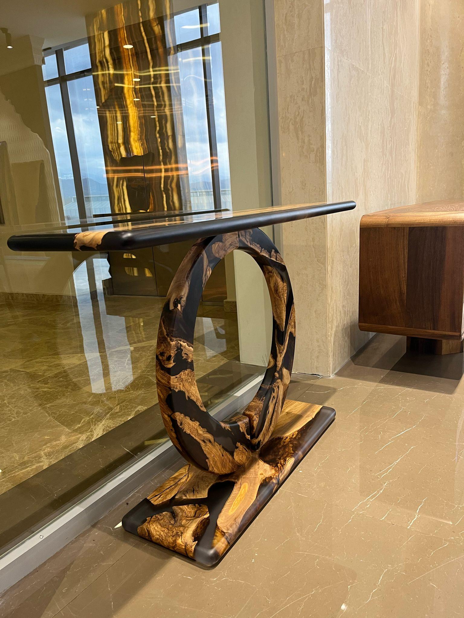 Wasserfall Olive Massivholz Epoxy Konsolentisch

Wir präsentieren unseren Konsolentisch aus Epoxy-Olivenholz - ein wahres Beispiel für Handwerkskunst und Eleganz. Dieses außergewöhnliche Möbelstück ist mehr als nur ein Couchtisch; es ist ein
