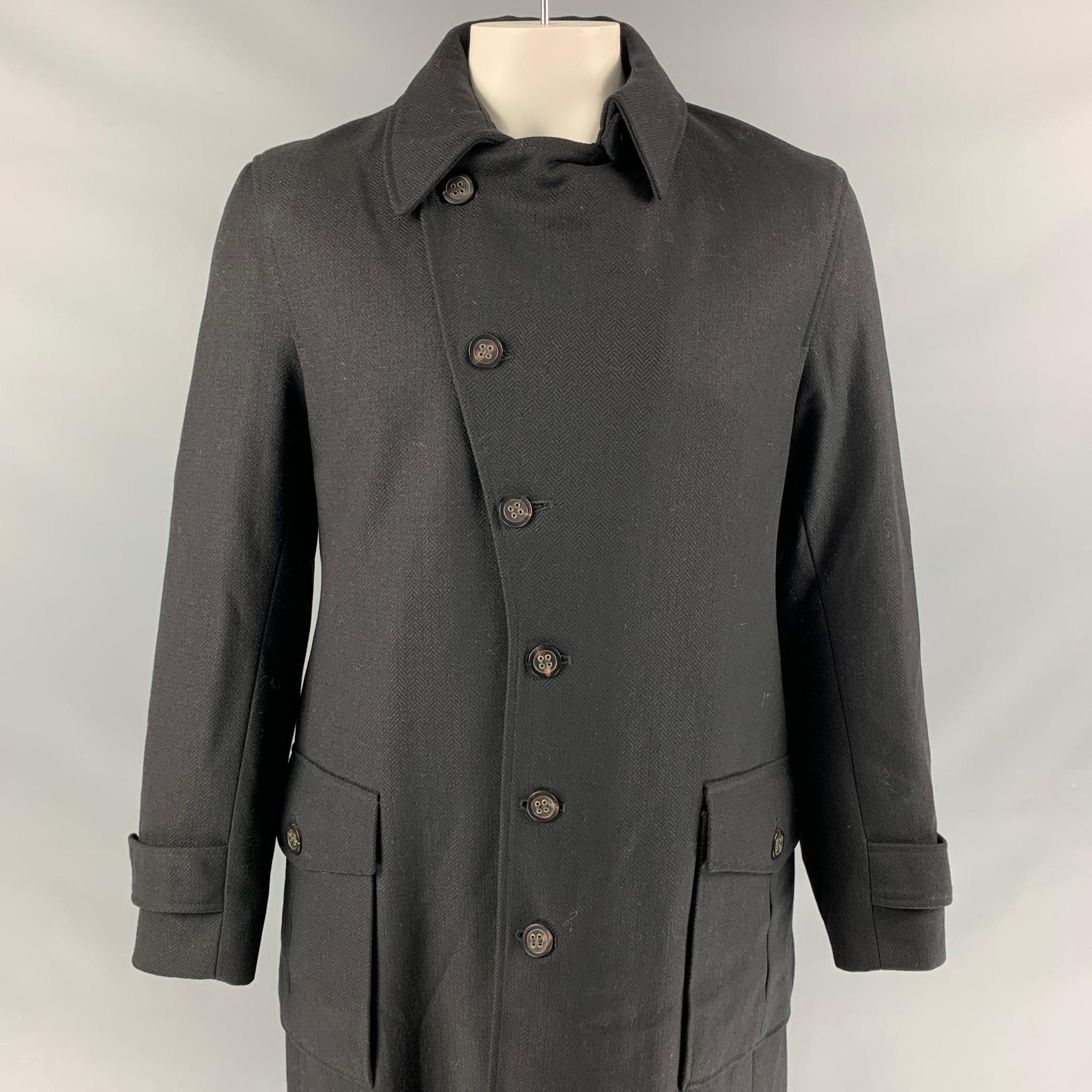 OLIVER SPENCER coat comes in a black herringbone wool with a full quilted liner featuring a spread collar, buttoned sleeves, patch pockets, back flap details, singe back vent, and a asymmetrical button closure. Made in England. 

Very Good Pre-Owned