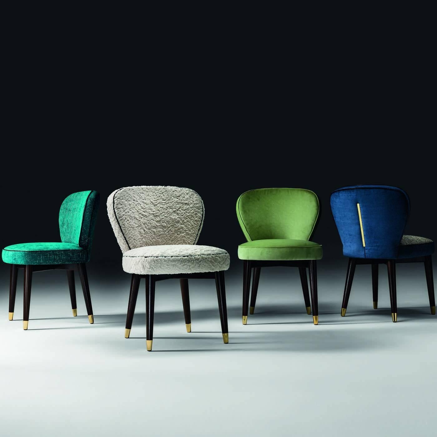 This elegant dining chair is also available as a stool. It is made in beechwood with padding in fire-resistant expanded polyurethane upholstered in fabric with dark accents marking its perimeter. The legs are in solid wood with gold-finished metal