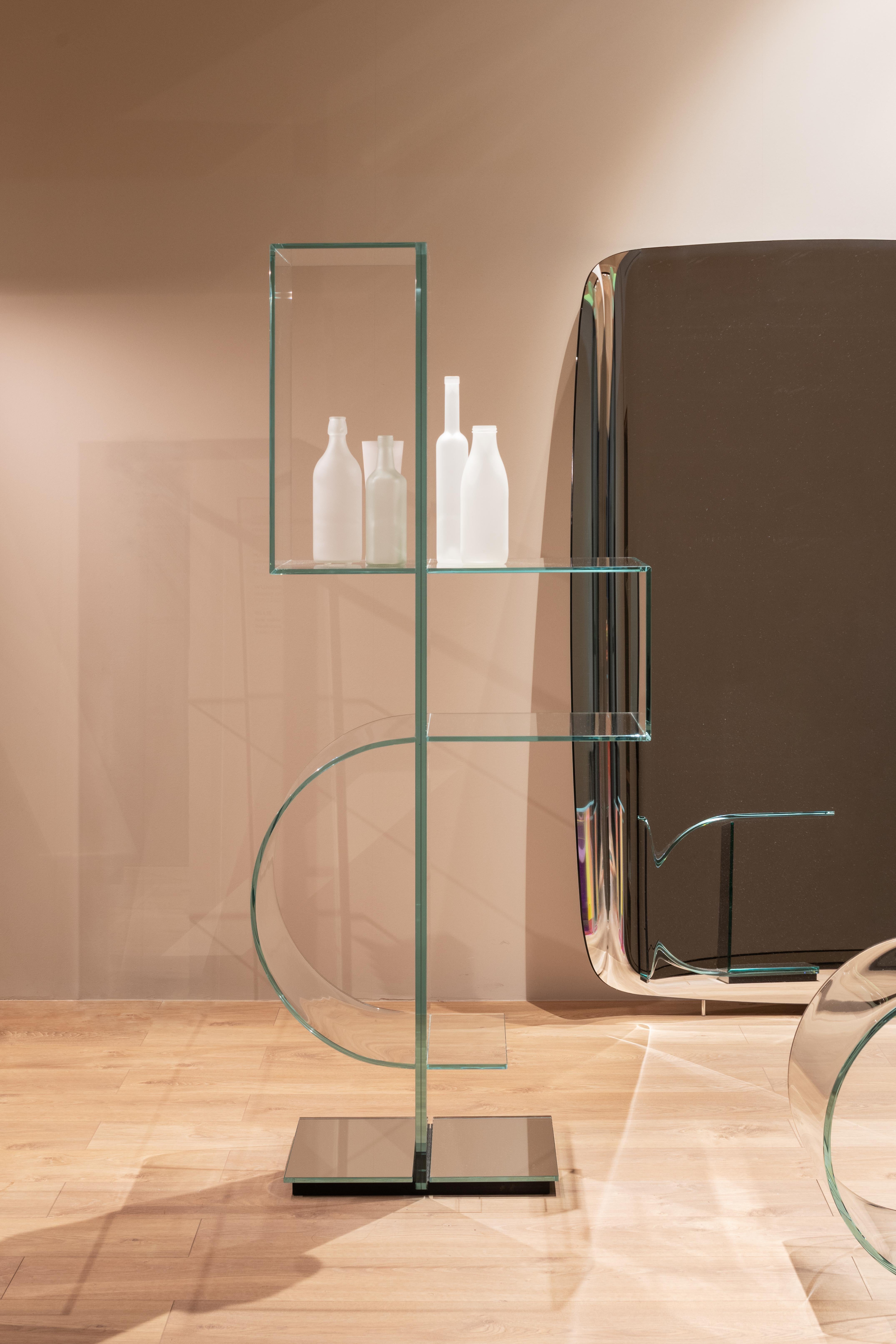 Freistehendes Totem-Bücherregal mit vertikaler Rückwand aus doppelseitigem, extra klarem Spiegel, laminiert 10+10 mm.
Die mit der Rückwand verklebten Regalböden bestehen aus 10 mm starkem, extraklarem Glas, das im 45°-Winkel verklebt ist, sowie aus
