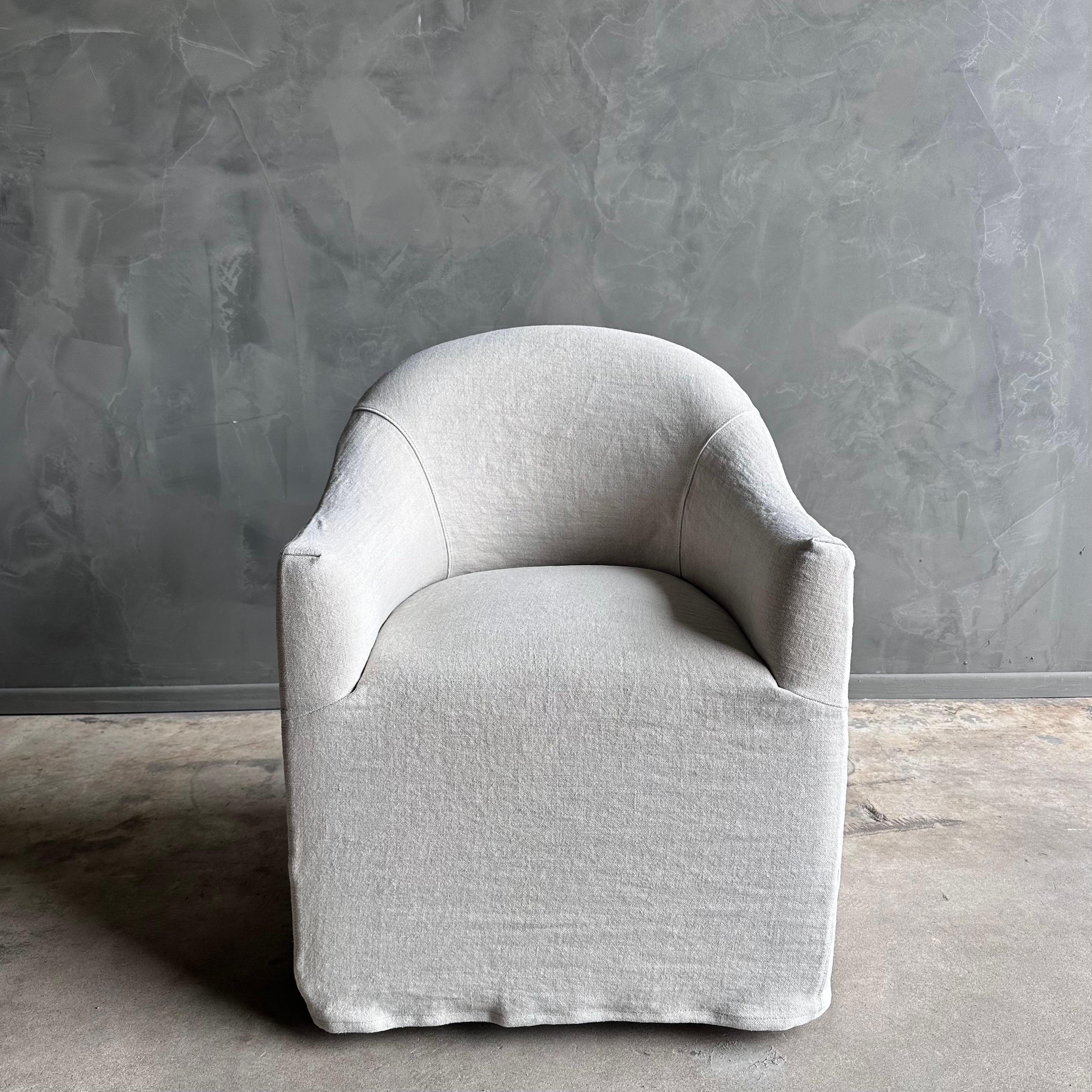 Introducing the Ollie Dining Room Chair, a perfect blend of style and functionality. This chair features a heavy stone washed linen slip cover in an elegant oatmeal greige color, giving it a sleek modern casual look. The soft hand of the linen adds