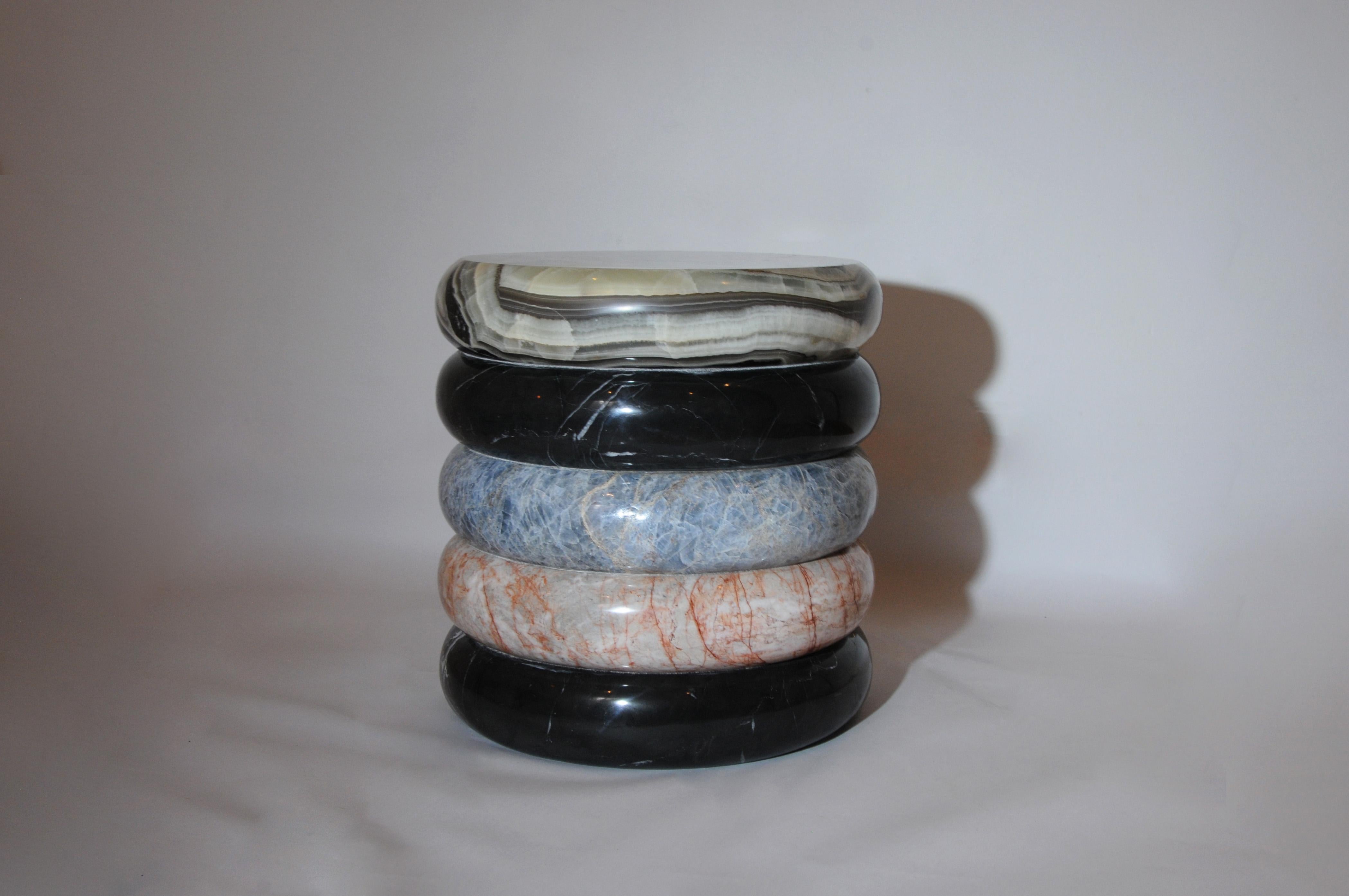 Rings of blue calcite, pink marble, black marble and green onyx tower to create Olo Nightstand Sculptural Side Table; a piece meticulously hand-sculpted from stones endemic to Mexico. The combination of materials, which reign over the piece’s final