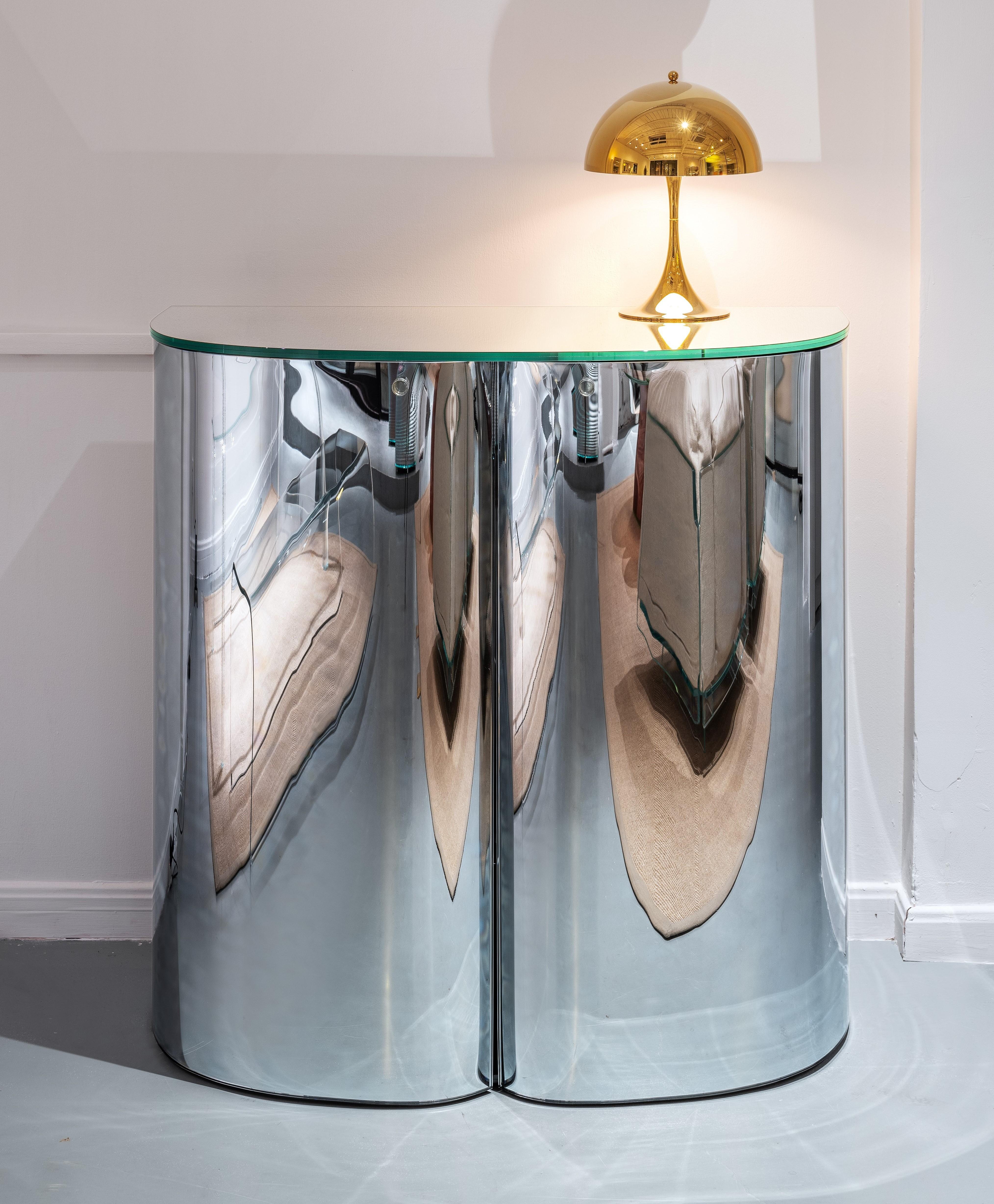 Storage units in a special mirrored glass with soft curved shapes.
The structure is in 6+6 mm laminated glass fully mirrored, both inside and outside.
The doors are in 6 mm curved and tempered double-sided mirrored glass, characterized by distorted
