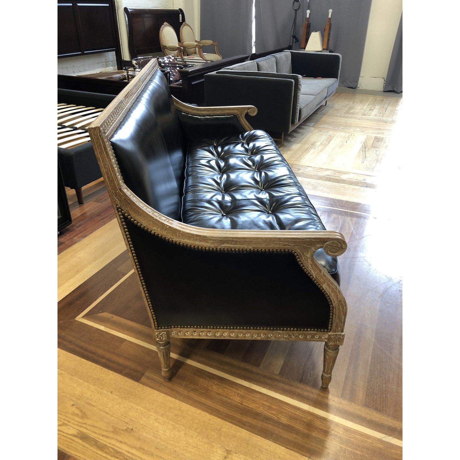 It presents a Hanna sofa by Oly Studio. Introducing a graceful French elegance to any room. It's square back and fluted legs are complemented by sophisticated carved details, plush upholstery and antique gold finish nailhead trim. The seat cushion