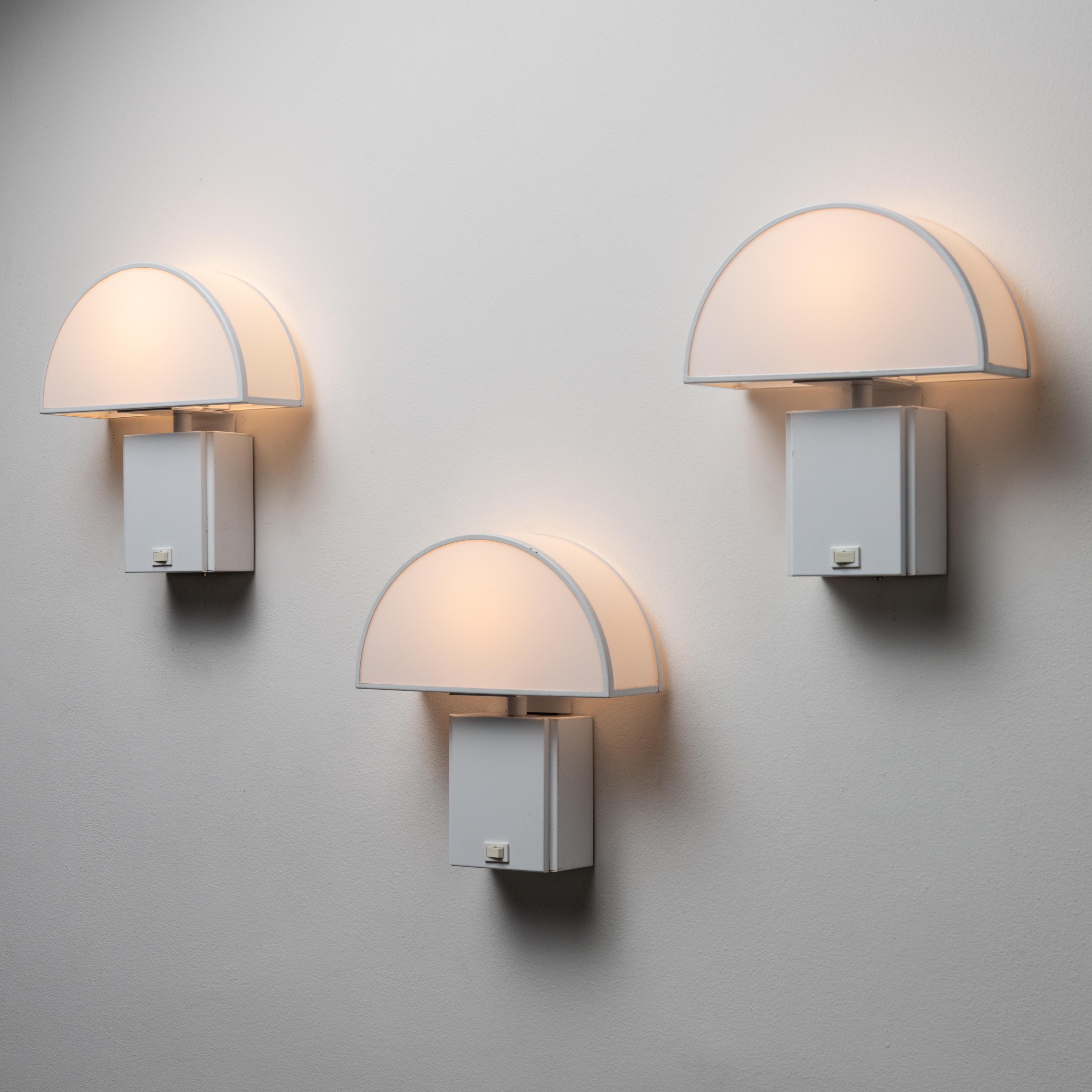 'Olympe' Sconces by Harvey Guzzini for ED. The 'Olympe' sconces feature a compact and rectangular body, with visible power switch on the center of the base along with a rounded umbrella-like shade that is framed in metal and diffused through acrylic