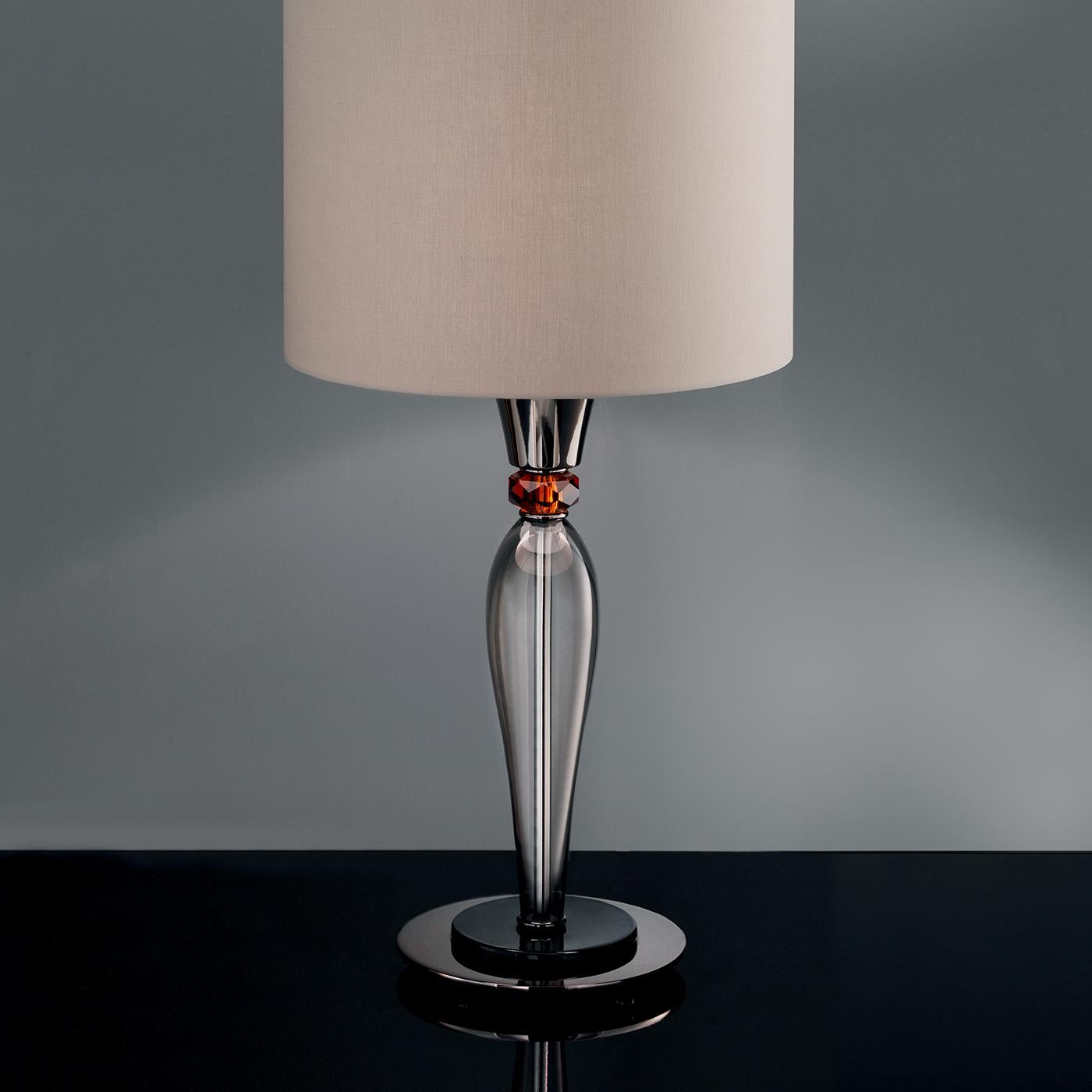 Available in many colors and finishes, this lamp features a cylindrical lampshade made of shiny chrome pvc on the inside and smokey transparent pvc on the outside. The small cup and the central part are made in Tuscany, while arms, crystal curls and