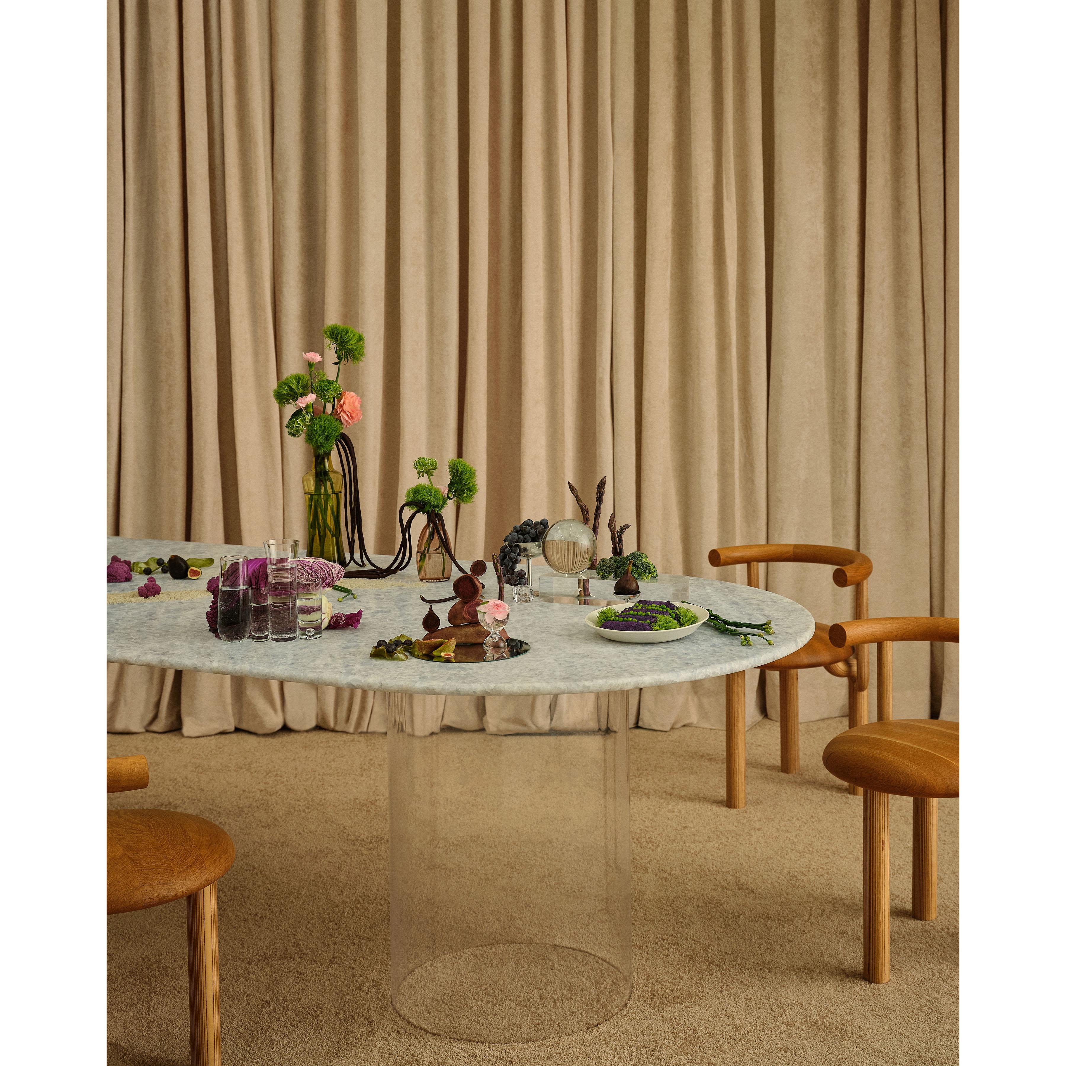 This pill-shaped dining table was originally designed for the Pieces Homes shoppable Airbnb in Kennebunk, Maine. The marble surface rests on top of a metal frame with collars that hold the plexi acrylic bases in place. Transparent bases give the