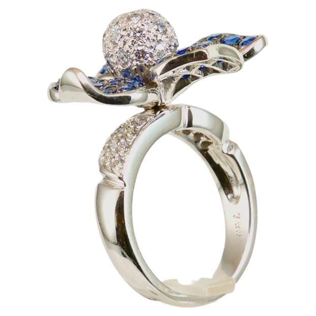 18K 750 Weißgold
1.00 Karat Diamant rund
3,34 Karat Saphir

Eine blaue Blume steht für Sehnsucht, Liebe und Inspiration. Sie ist eine Blume, die das metaphysische Streben nach dem Unmöglichen und Unendlichen darstellt. Die Farbe Blau in der Blume