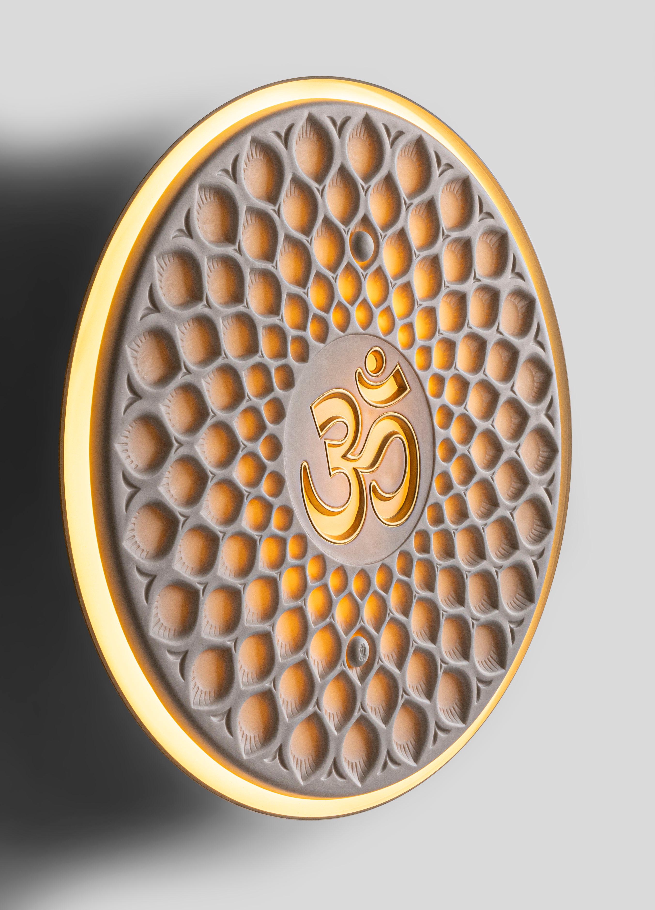 Applique en porcelaine avec un design décoratif représentant la syllabe sacrée Om. Om est la syllabe sacrée qui symbolise l'unité avec le suprême, la conjonction du physique et du spirituel. C'est un mantra essentiel dans les religions dharmiques