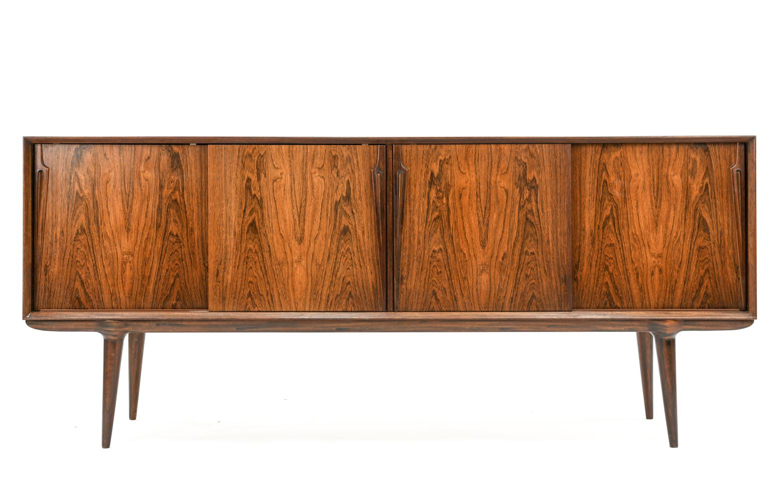 This Danish midcentury rosewood sideboard was produced by Oman Jr., possibly model 13. Featuring book-matched rosewood veneer, elongated cabinet door handles, and a refined base to add attractive elevation to the body of the cabinet. This sideboard