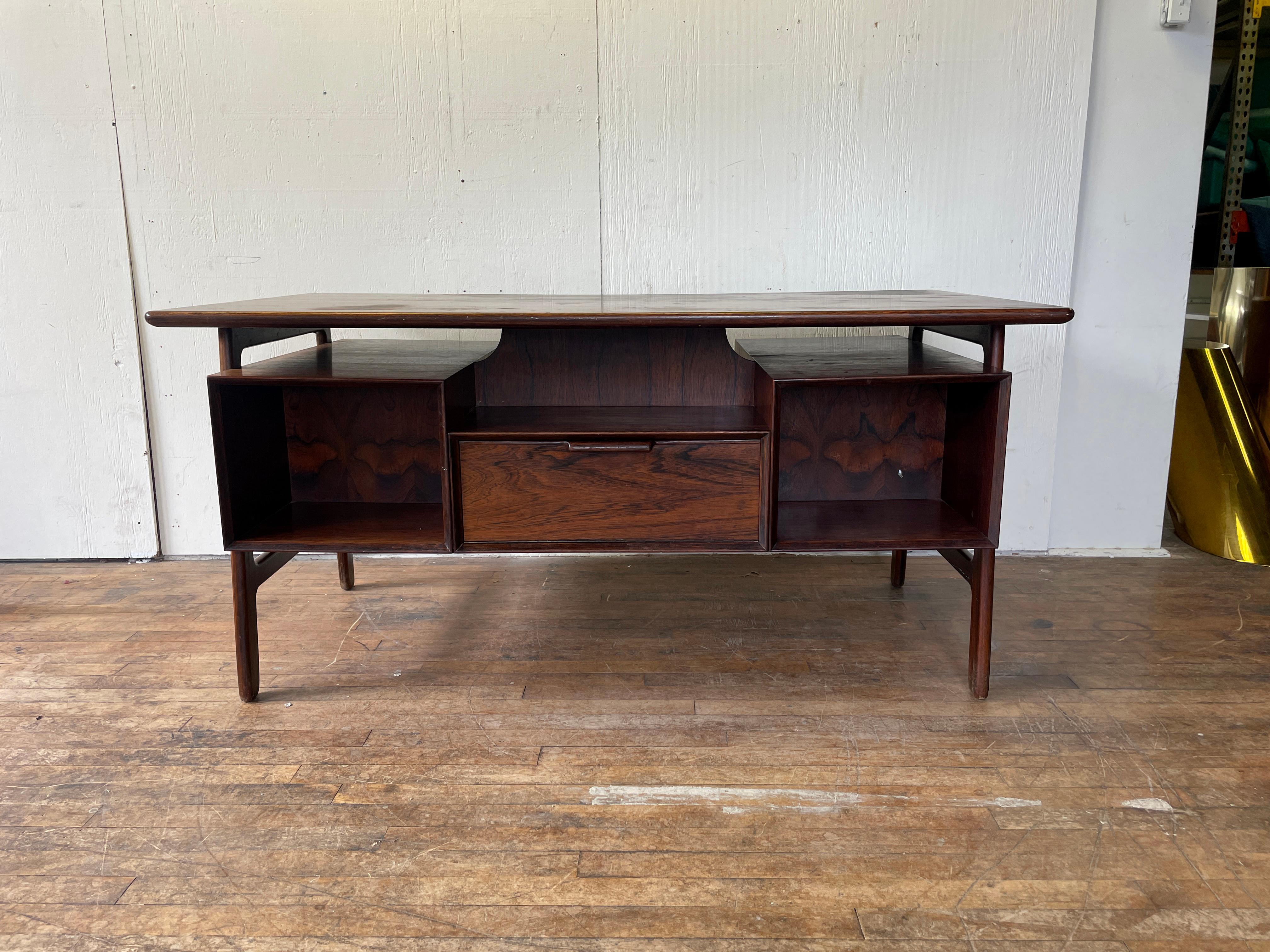 A rare danish-modern rosewood executive desk by Omann Jun. With six drawers, one rear cabinet, and two bookcase alcoves, this desk is packed with storage. The floating design also allows for convenient placement of folders, notebooks, or a laptop on