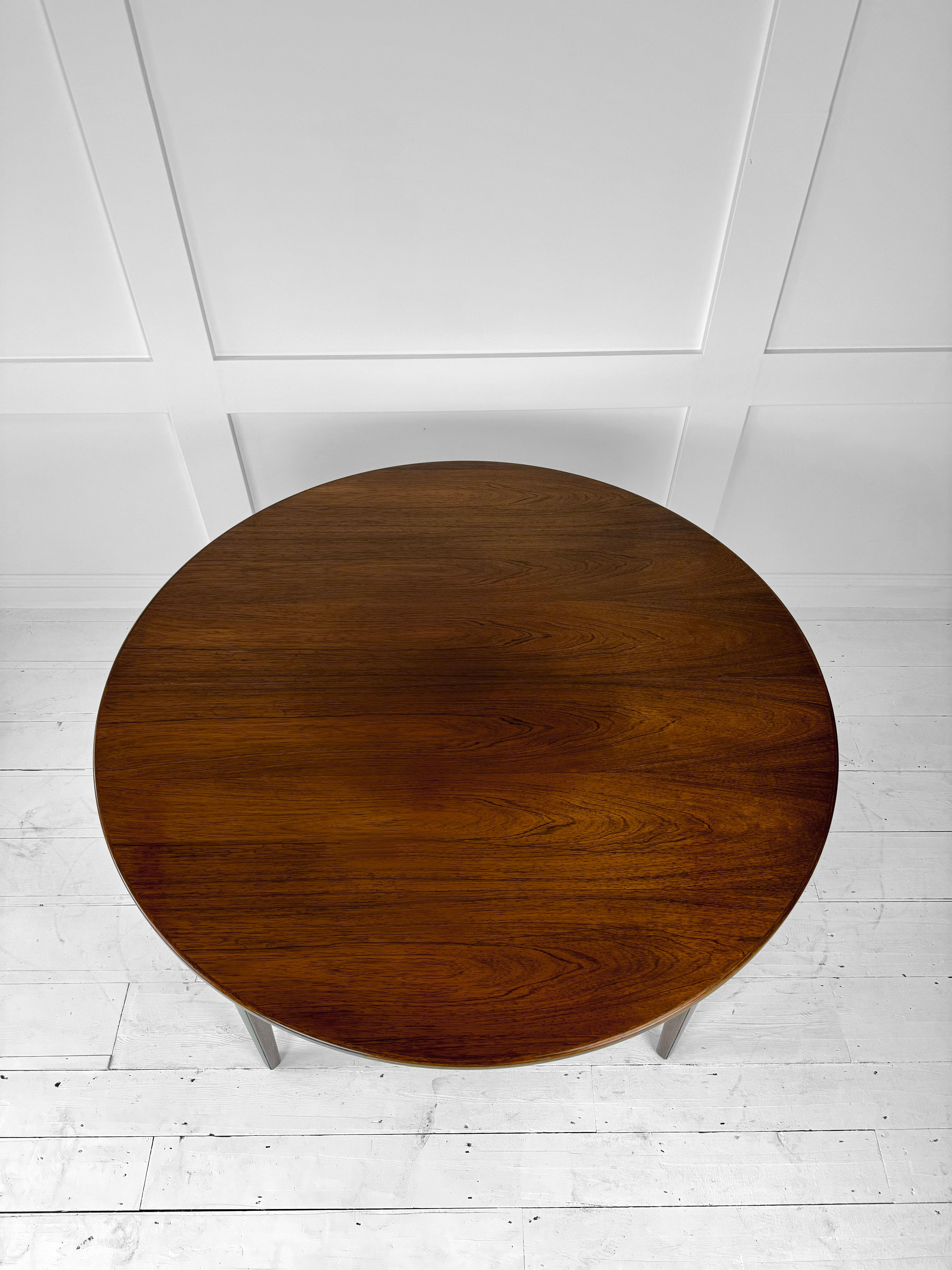 Cette table à manger à rallonge en bois de rose Omann Jun modèle 55 pour Omann Jun Møbelfabrik, est une pièce étonnante qui incarne le design emblématique du mobilier danois des années 1960. Fabriquée à partir d'un riche bois de rose, cette table