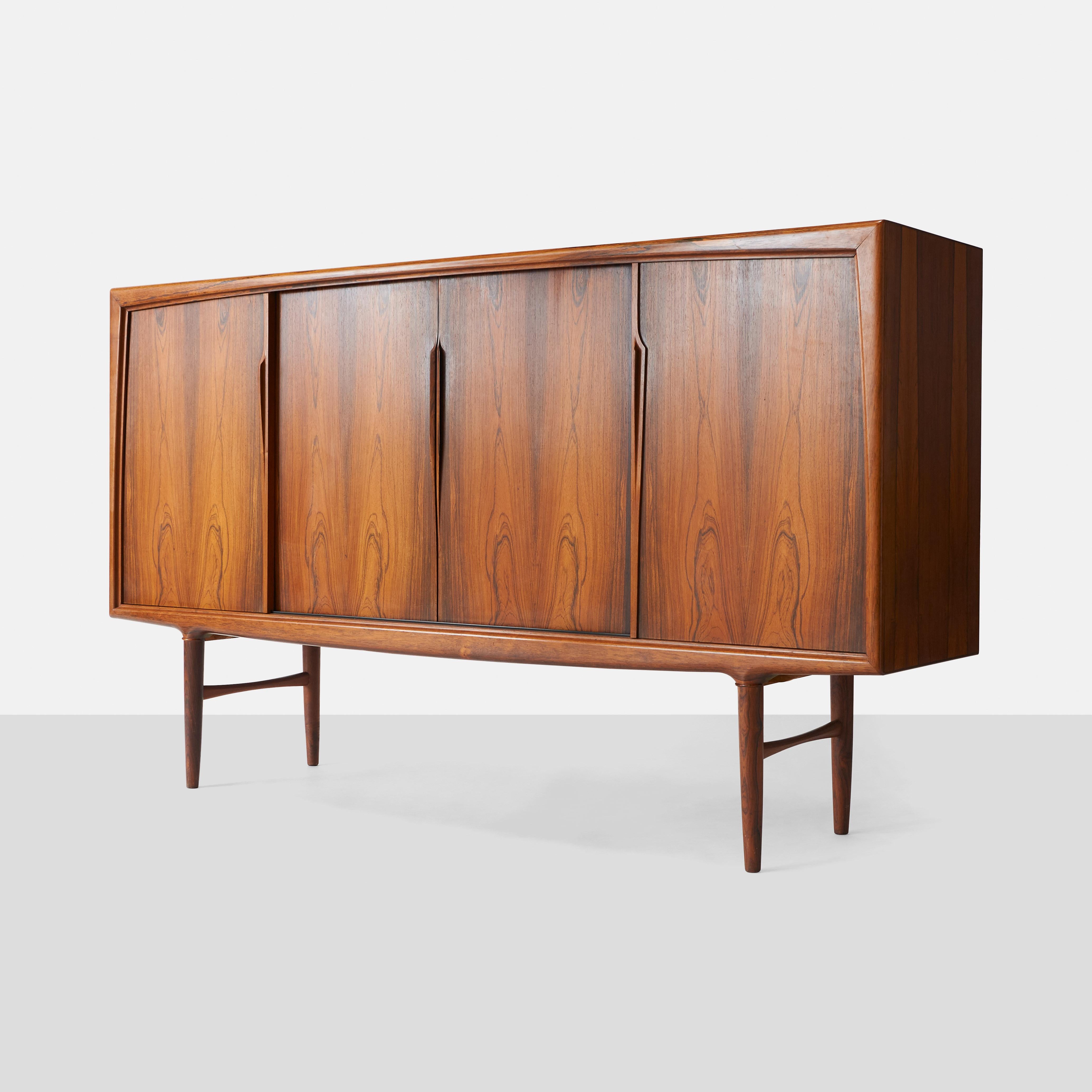 A lovely sideboard of rosewood by Omann Jun. Curved front with four sliding doors enclosing adjustable shelve and five lined drawers. Rosewood interior.

Model #19.