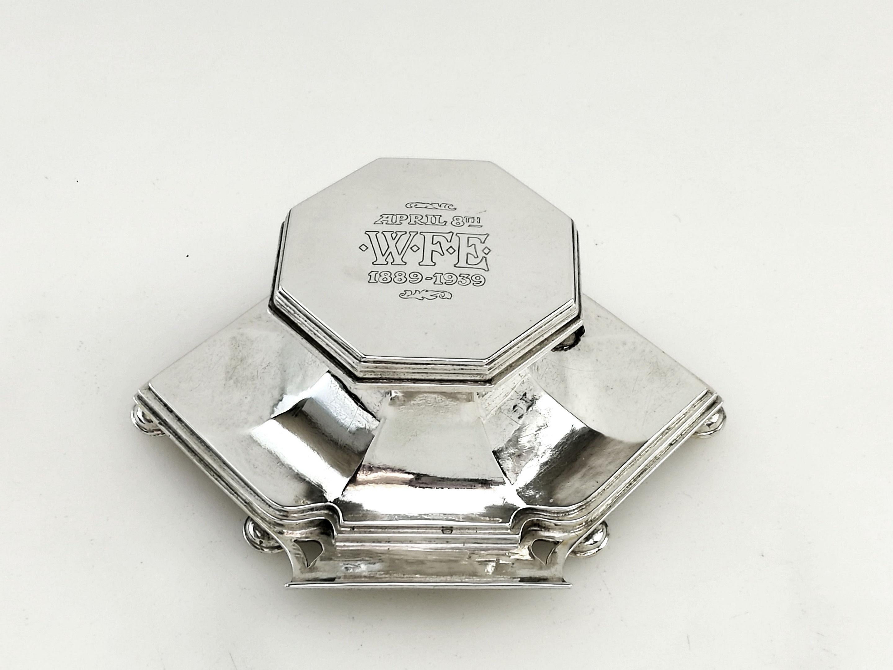 A wonderful Arts & Crafts solid silver Inkwell with a hexagonal lid and an elongated hexagonal base. The base stands on 6 ball feet and has two pen rests, on in the front and one at the back. The base curves up to the rim in elegant panels and the