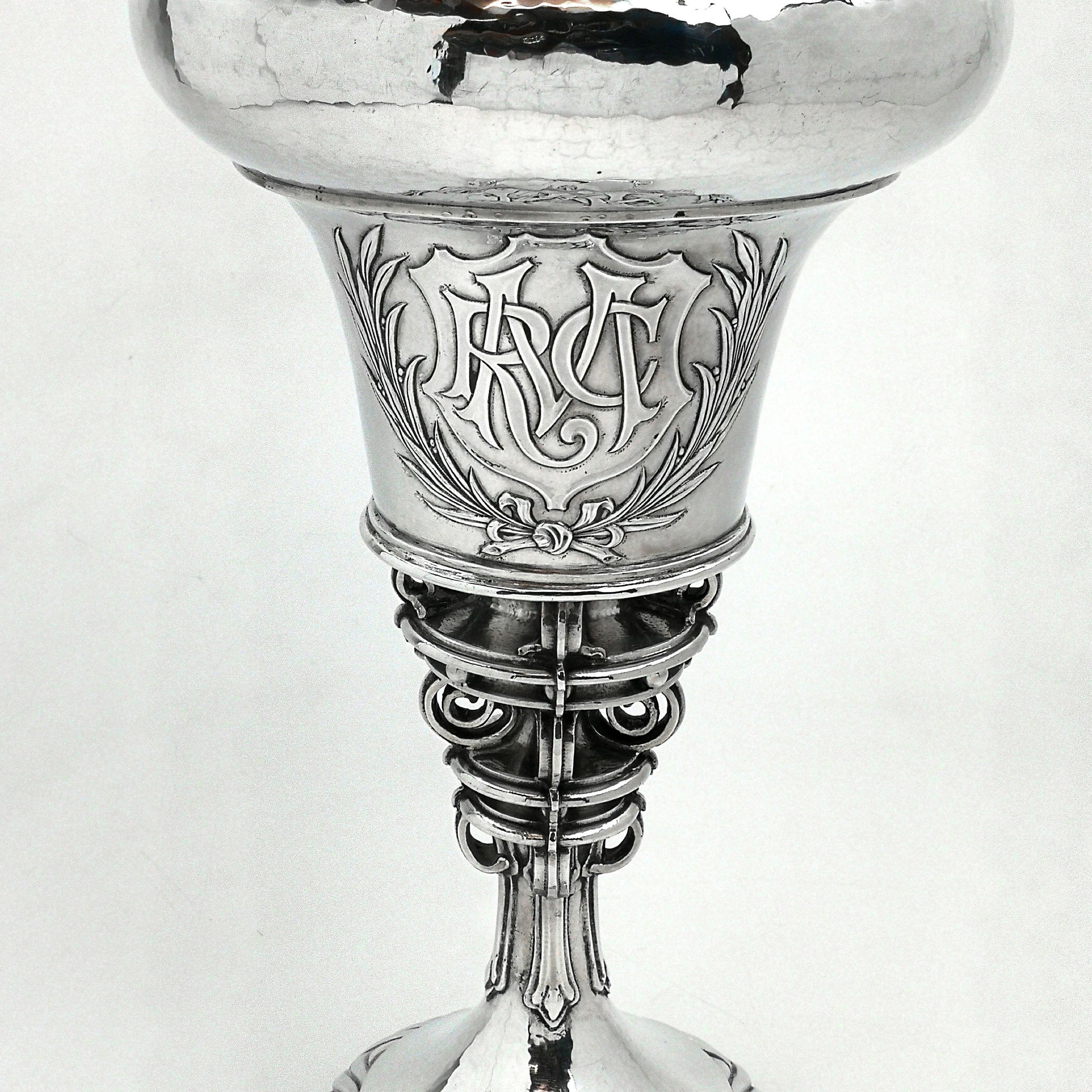 A magnificent Arts & Crafts solid Silver Cup and Cover by master Silversmith Omar Ramsden. This tall Lidded Cup features an ornate graduated column and has a shield shaped monogram above a wreath applied to the one side. The Cup has a domed fitted