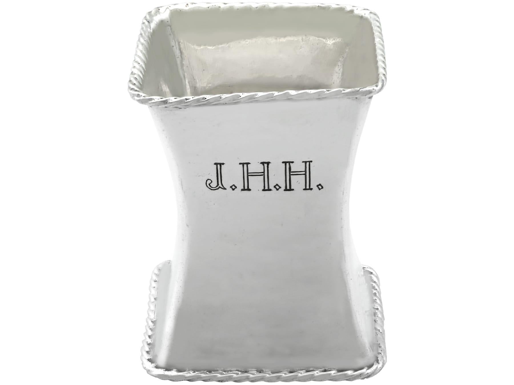 This exceptional antique George V sterling silver napkin ring has a square form with rounded corners.

The large and elongated waisted surface of this Omar Ramsden napkin ring is embellished with the contemporary engraved initials 'J.H.H'.

The