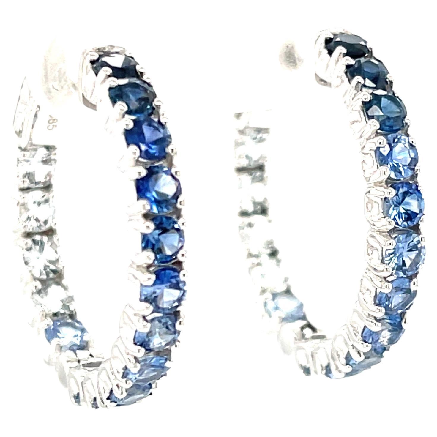 Bellezza, lusso e raffinatezza sono incarnati in questo paio di eleganti orecchini a cerchio con zaffiri ombreggiati, caratterizzati da una straordinaria e insolita collezione di zaffiri blu e bianchi. Oltre 4 carati di zaffiri brillanti che si