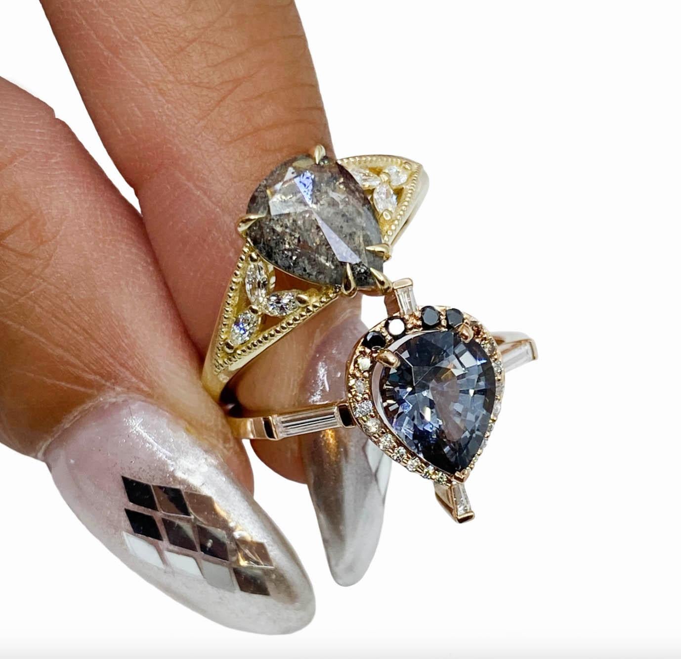 An ombre cascade of diamonds surrounds a pear shape Thai grey spinel, set in 14k rose gold. 

Materials: 14K Rose Gold + 1.5ct pear spinel with approximately .33ctw melee diamonds in champagne, black, and white. 

Size: 7