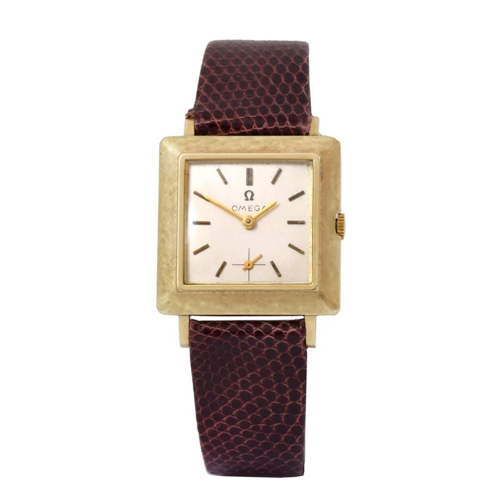 Découvrez l'élégance de la montre OMEGA Vintage By 1960's 14KT Gold 27mm x 27mm Square Case. Avec ses flancs inclinés Florentine et son cadran beige orné d'index bâtons en or plein, ce garde-temps dégage un charme intemporel. Le cadran auxiliaire