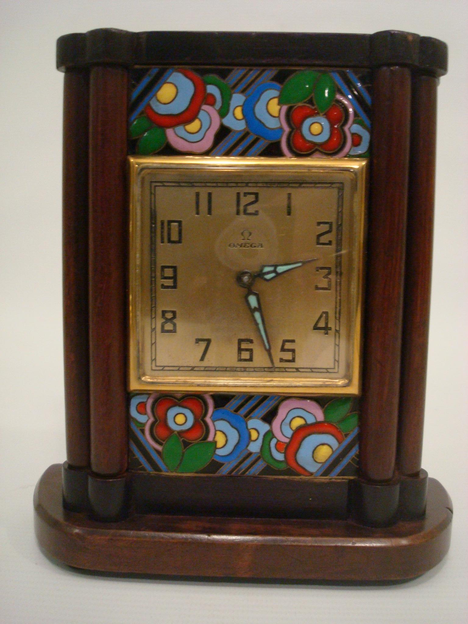 Omega. A wood and enamel Art Deco eight day desk clock
Singed Omega.
Polished wooden case, two polychrome enamel panels with floral and geometric motif, gilt case back, dial signed.
Very good conditions.
Working conditions. It just been