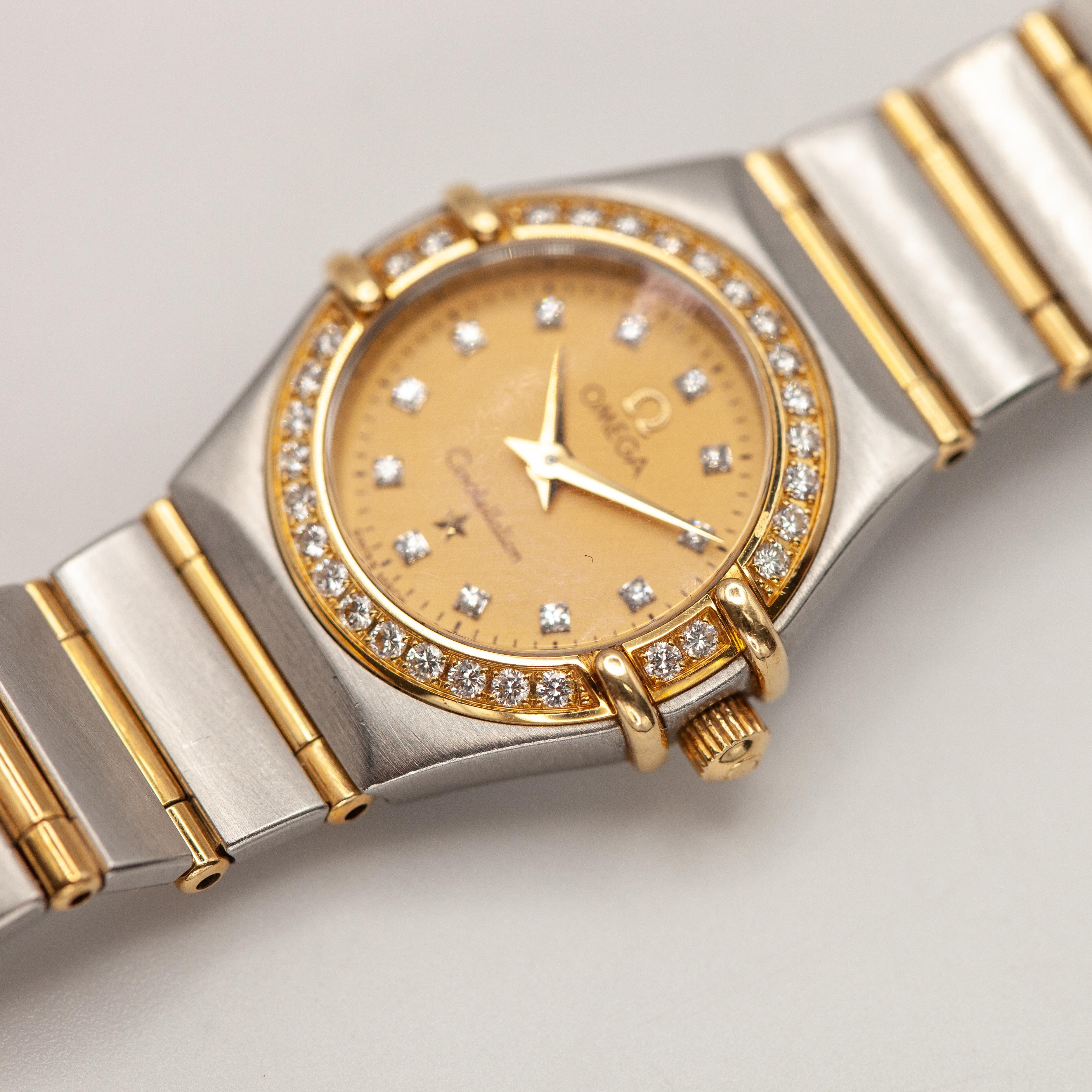 Une montre Omega Constellation raffinée pour femme, réalisée en or jaune 18 carats et en acier inoxydable. Le cadran et la lunette champagne sont ornés de diamants de taille ronde. Le bracelet intégré présente une alternance de maillons en or et en