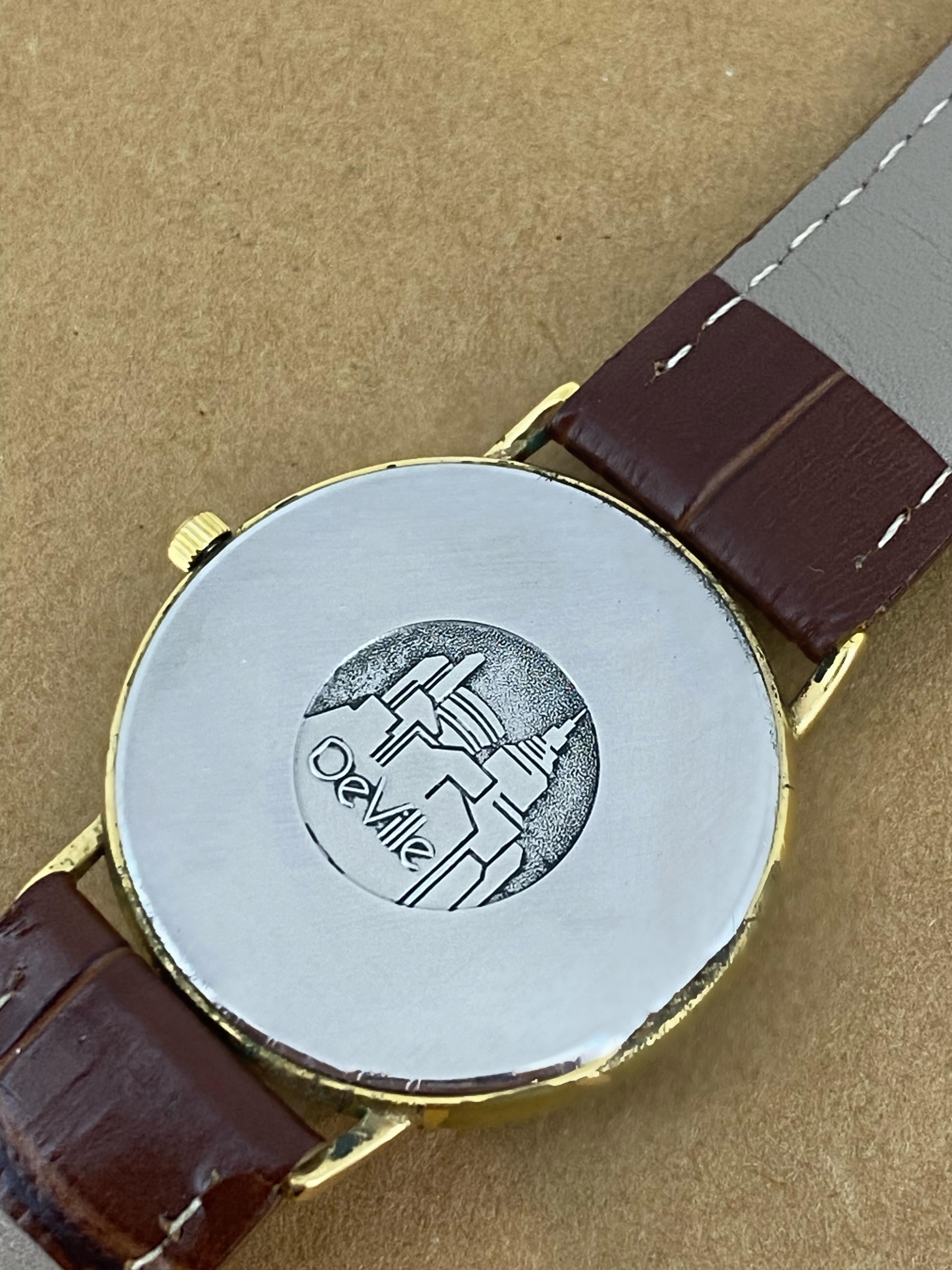 Diese elegante und vielseitige Omega De Ville-Uhr aus den 1980er Jahren
Merkmale:  

Rundes Gehäuse aus 18 Karat vergoldetem S/Stahl, 
von 32 mm, 
Gehäuseboden ist signiert und trägt ein De Ville-Logo 

Ausgestattet mit einem Schweizer