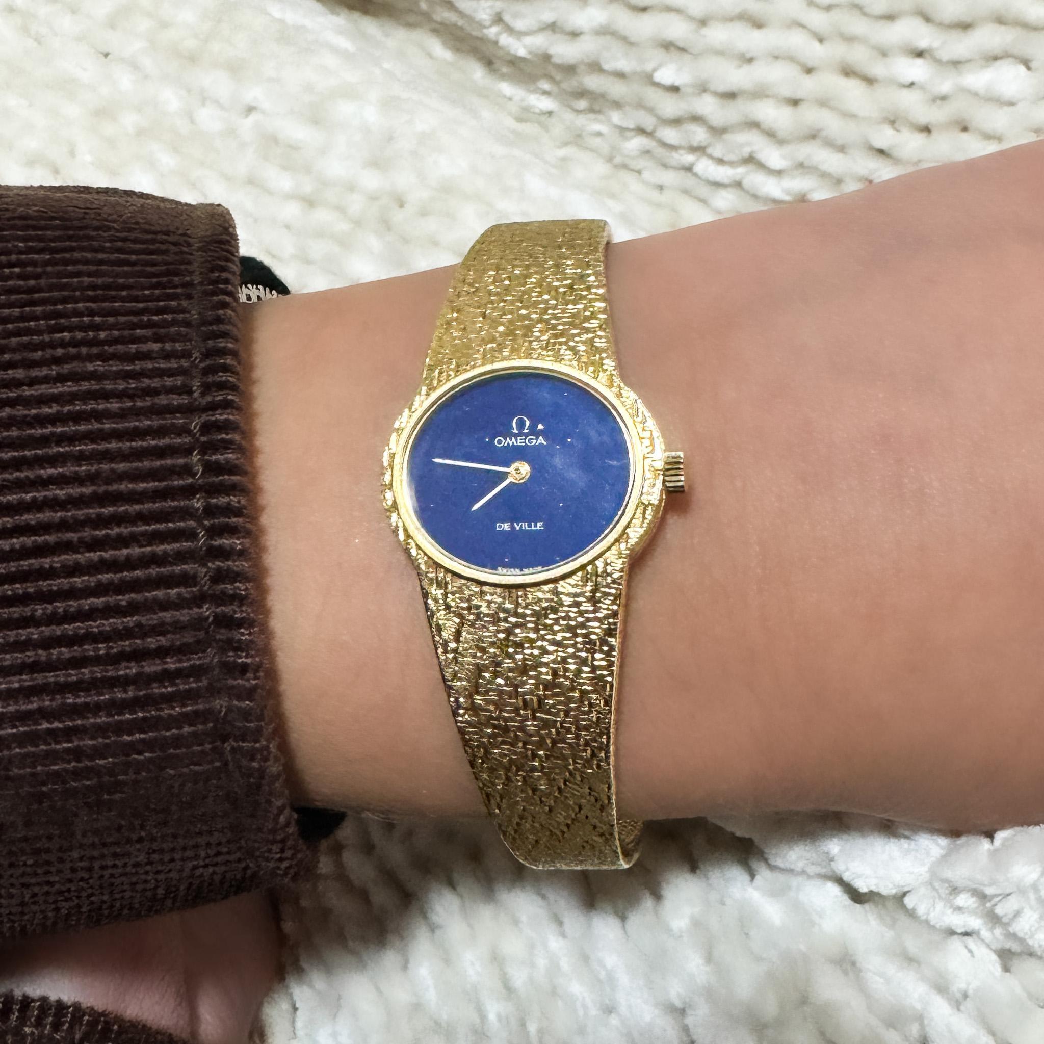 Vintage Omega De Ville Handaufzugsuhr in 18K Gelbgold mit einem seltenen Lapislazuli-Zifferblatt und strukturiertem Goldarmband. CIRCA 1970er Jahre, diese elegante Damenuhr misst 7 Zoll und ist leicht verstellbar.

Einzelheiten:
Artikel Typ: Vintage