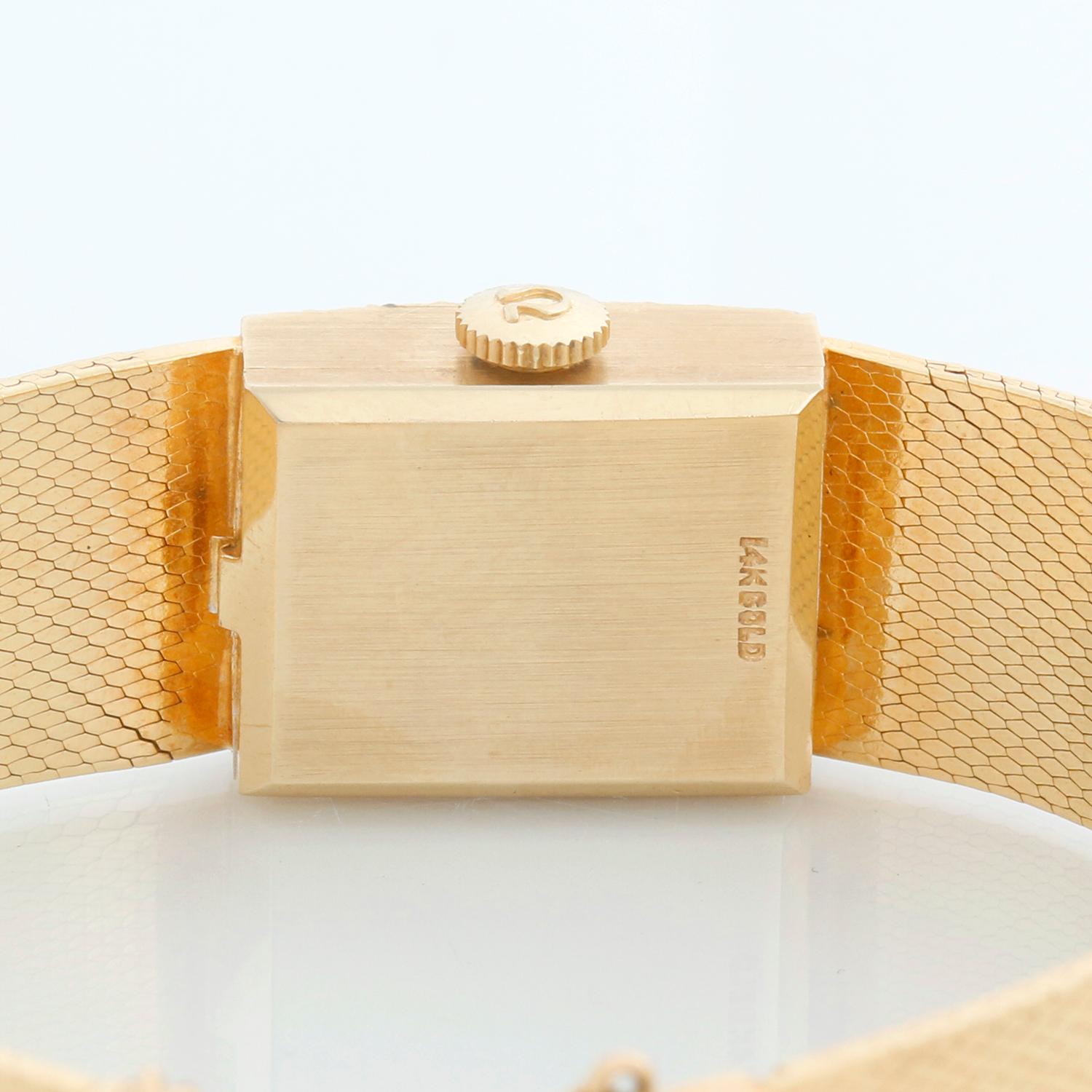 Omega DeVille Montre habillée pour homme en or jaune 14 carats - Quartz. Boîtier en or jaune 14k avec lunette en diamant d'usine (14 mm x 18 mm). Cadran texturé or avec index bâtons. Bracelet intégré en maille d'or jaune 14k ; convient à un poignet