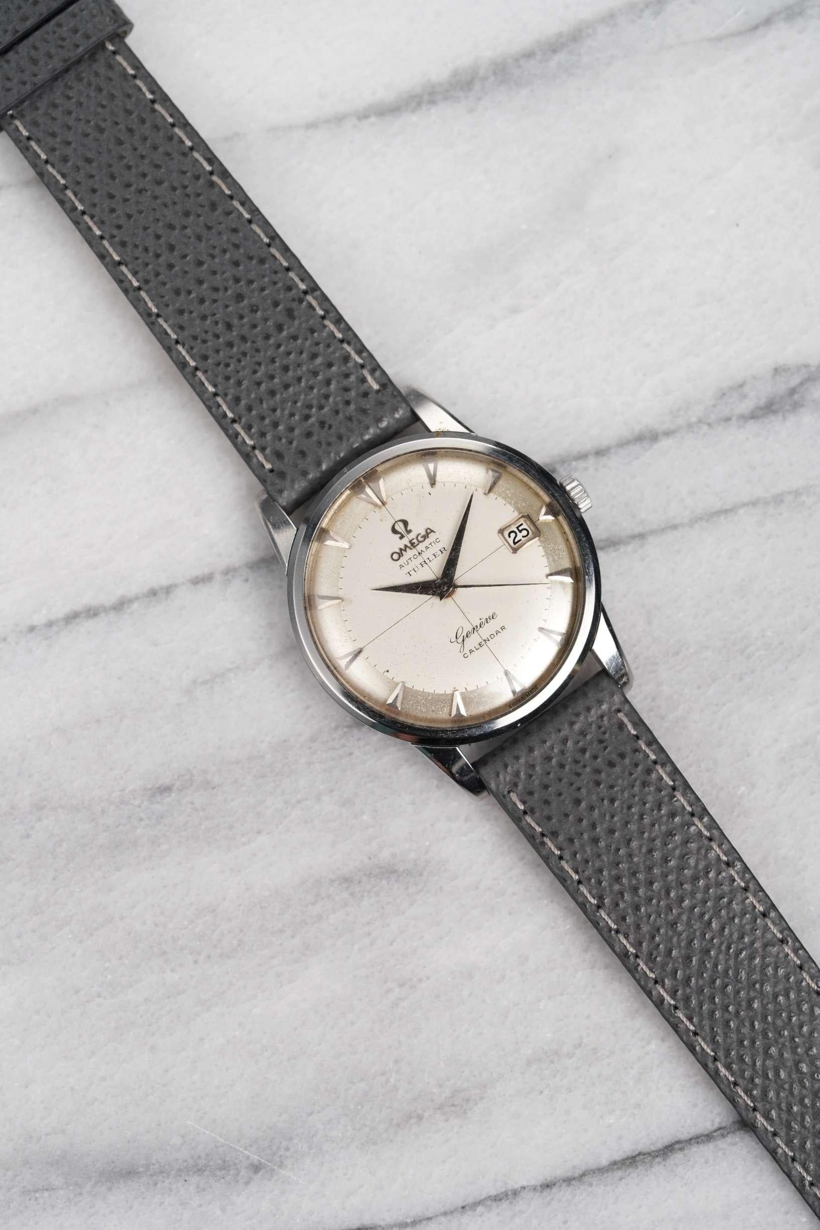Aquí tienes un reloj automático Omega Geneve con esfera plateada de los años 60. Las medidas incluyen una caja de 34 mm y una anchura de orejetas de 18 mm. Lleva una correa de cuero gris de recambio (Made in Italy). Caja de acero. Agujas e índices