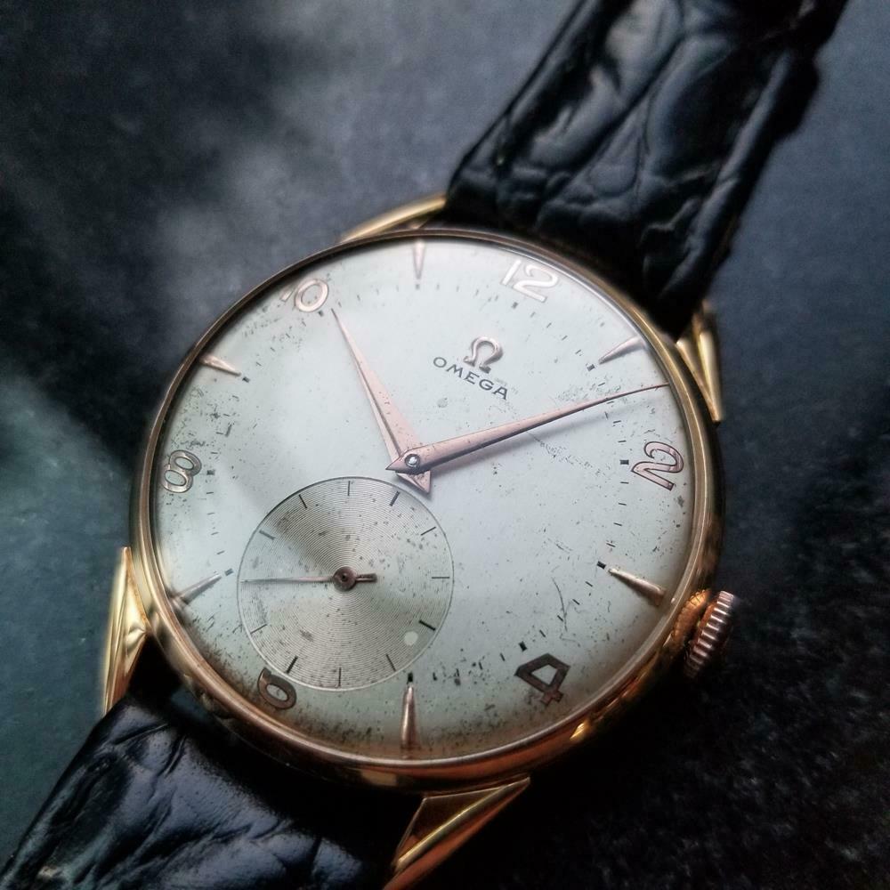 Luxurious classic, men's 18k solid rose gold Omega manual wind dress watch, c.1950s. Verified authentic by a master watchmaker. Gorgeous silver Omega signed dial, alternating gold arrowhead and Arabic numeral hour markers, gold minute and hour