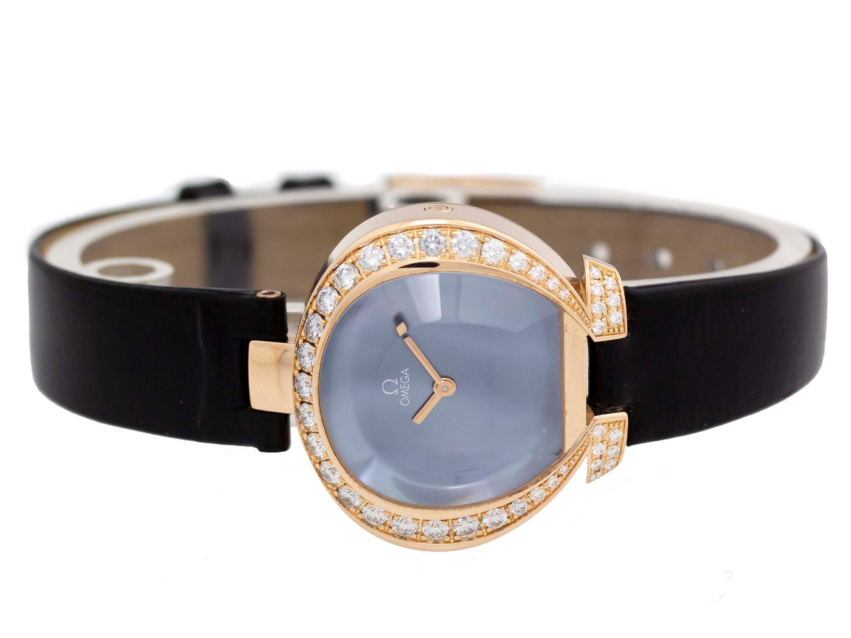 18k red gold Omega Omegamania quartz watch with a 27mm case, blue dial, diamond bezel, and black leather strap with tang buckle. Features include hours and minutes. It comes with Omega Box and a 2 Year