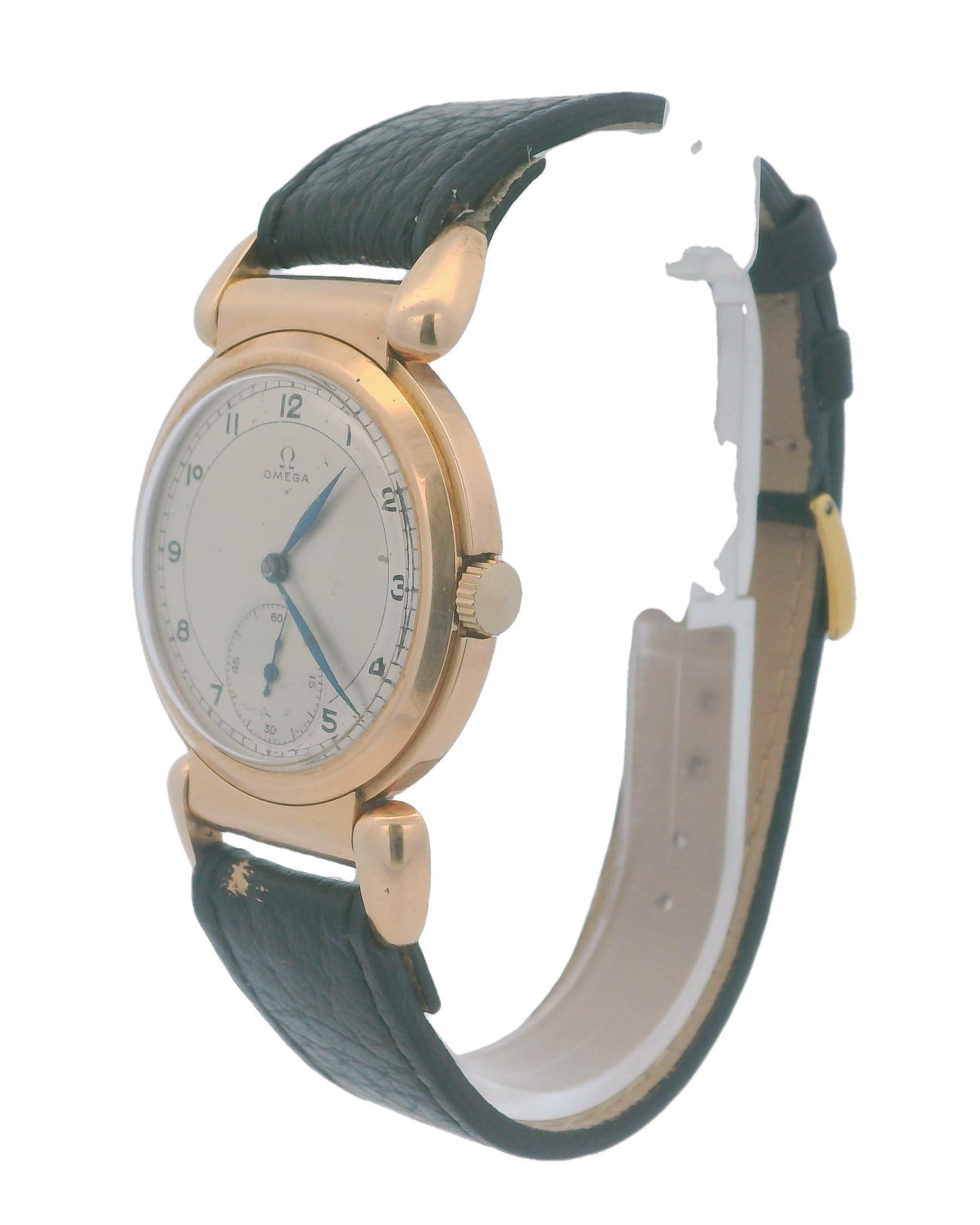 A classic Omega Scarab wristwatch from 1930. This exquisite timepiece is crafted in 14k rose gold and features a round case with a manual movement. The silver dial, while still elegant, shows some age-related marks that add character to its vintage