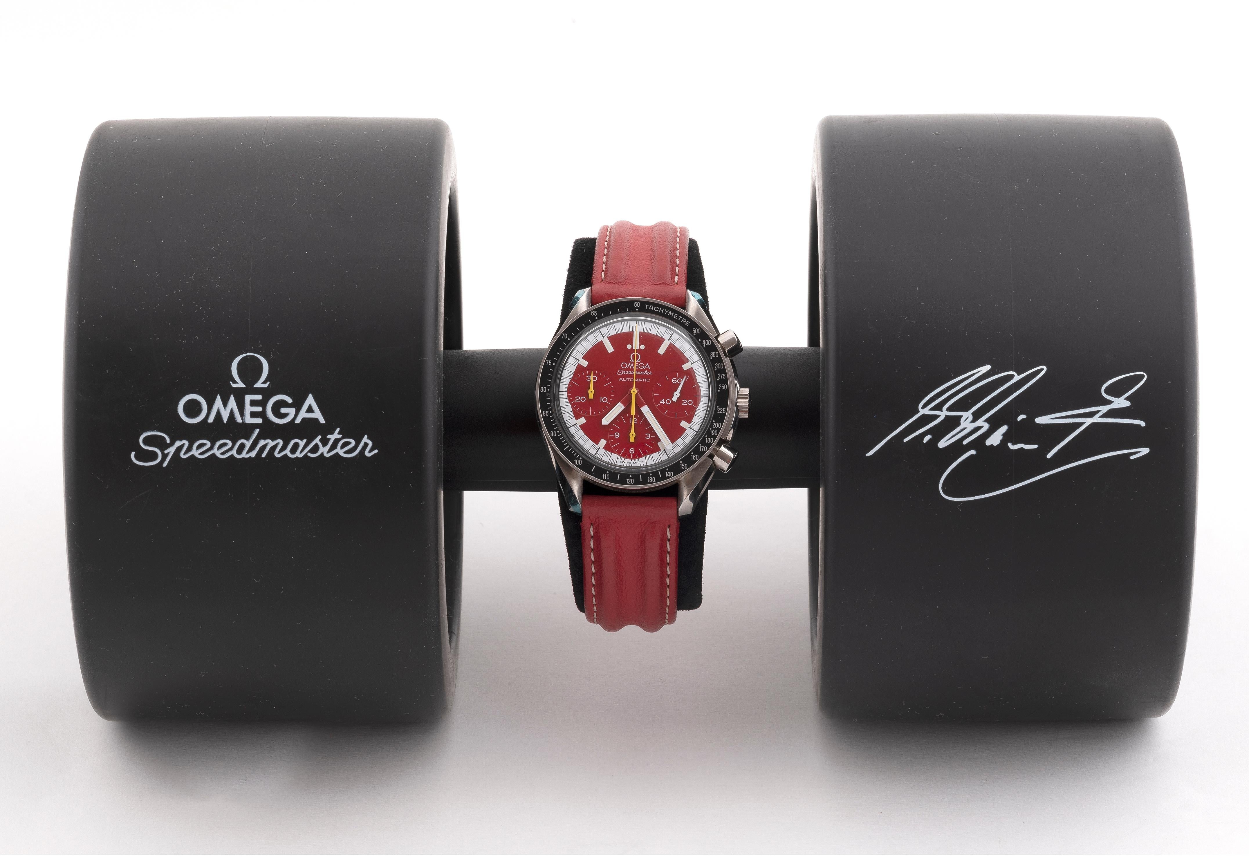 This 39mm. OMEGA SPEEDMASTER Michael Schumacher edition comes complete with everything from 2001. The very cool collapsing dual tire holder, cards and box are all complete. The rubber tire holder has some wear in the writing, which his tends to rub