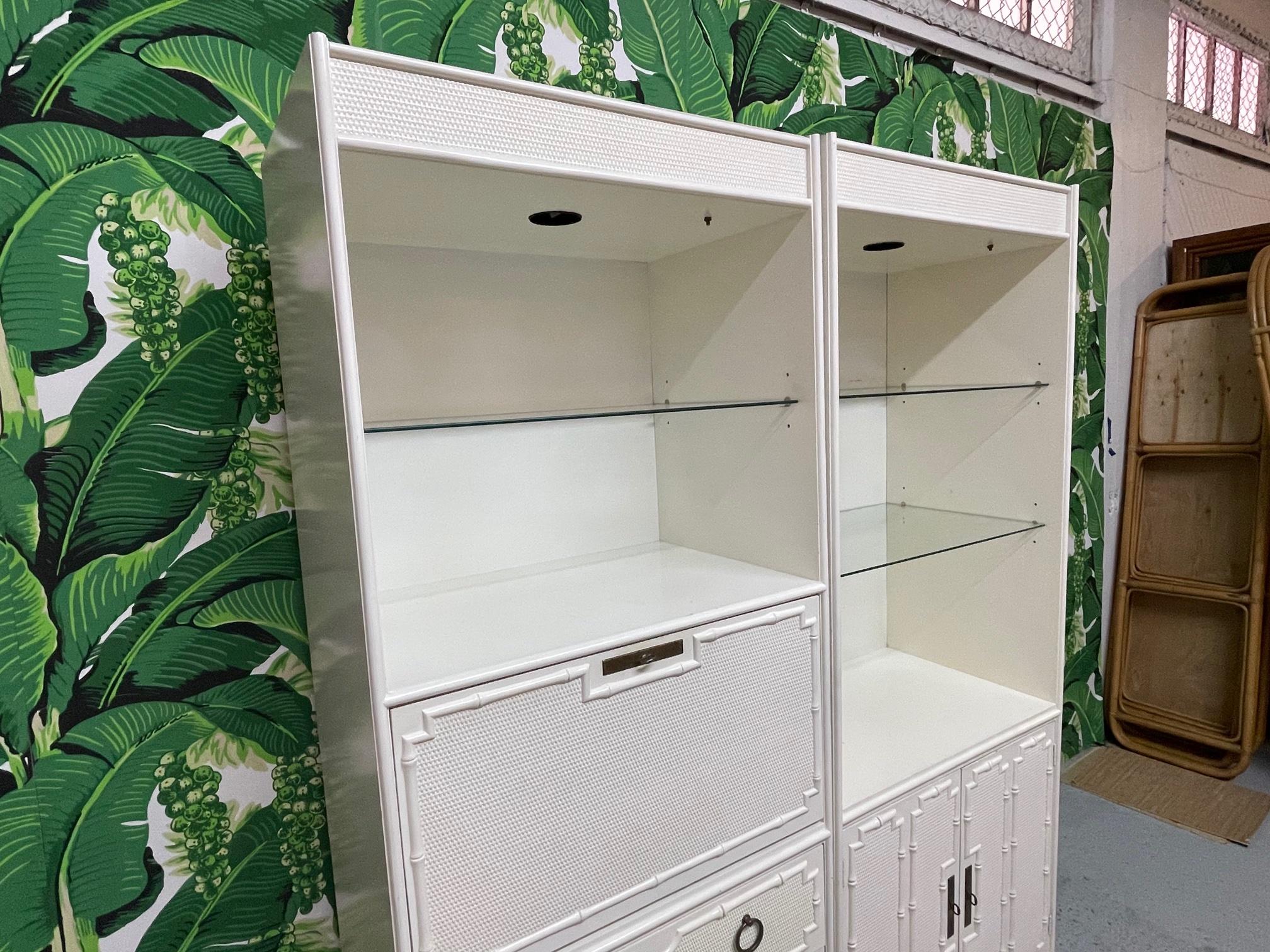 Two-piece lighted bookshelf/étagère/wall unit features bright white finish and glass shelving. Drop desk and 3 drawers in one unit along with shelving and double door storage in the other. Faux bamboo detailing. Attributed to Omega. Good condition