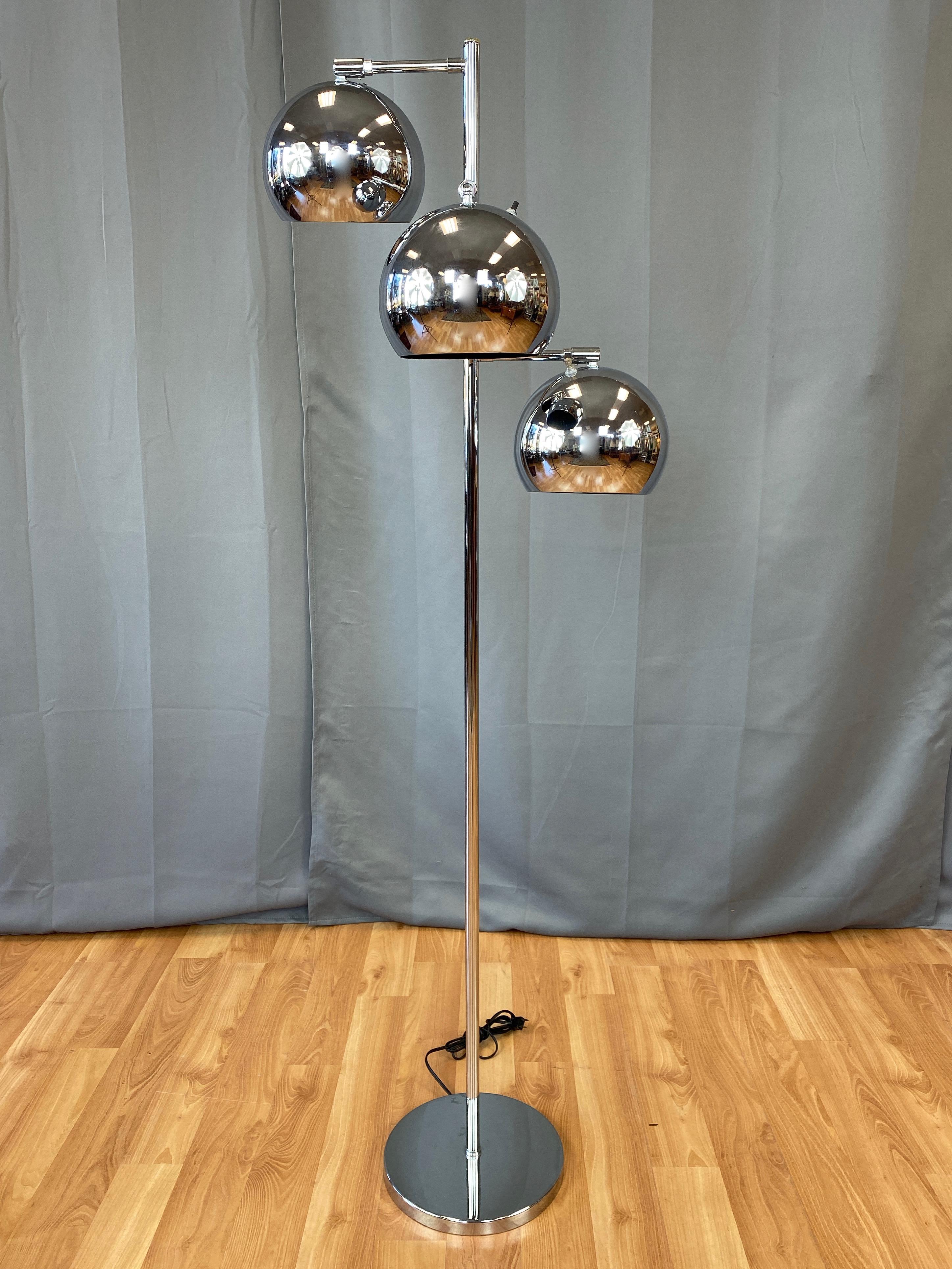 A late 1960s chrome floor lamp with a trio of articulated orb lights by OMI for Koch & Lowy. 

Gleaming eyeball-style globe shades with matte black interiors rotate and swivel on fixed arms, allowing for precise positioning of each independently