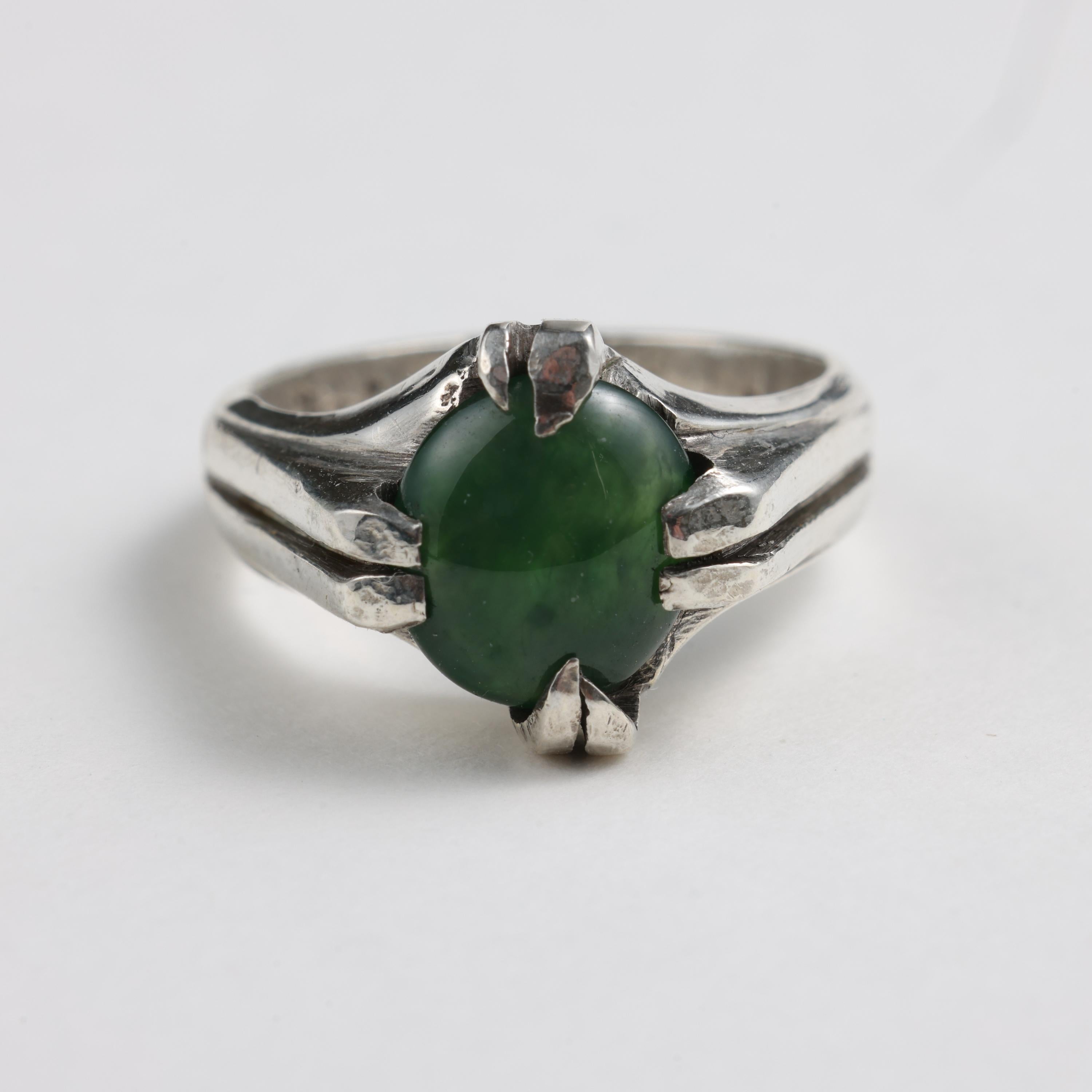 This gorgeous size 6 ring was handmade from silver and is constructed to apocalypse-survival standards. The forest-green omphacite jade compliments the rustic, heavy patina of the silver with its high-gloss polish.

The silver mounting is somewhat