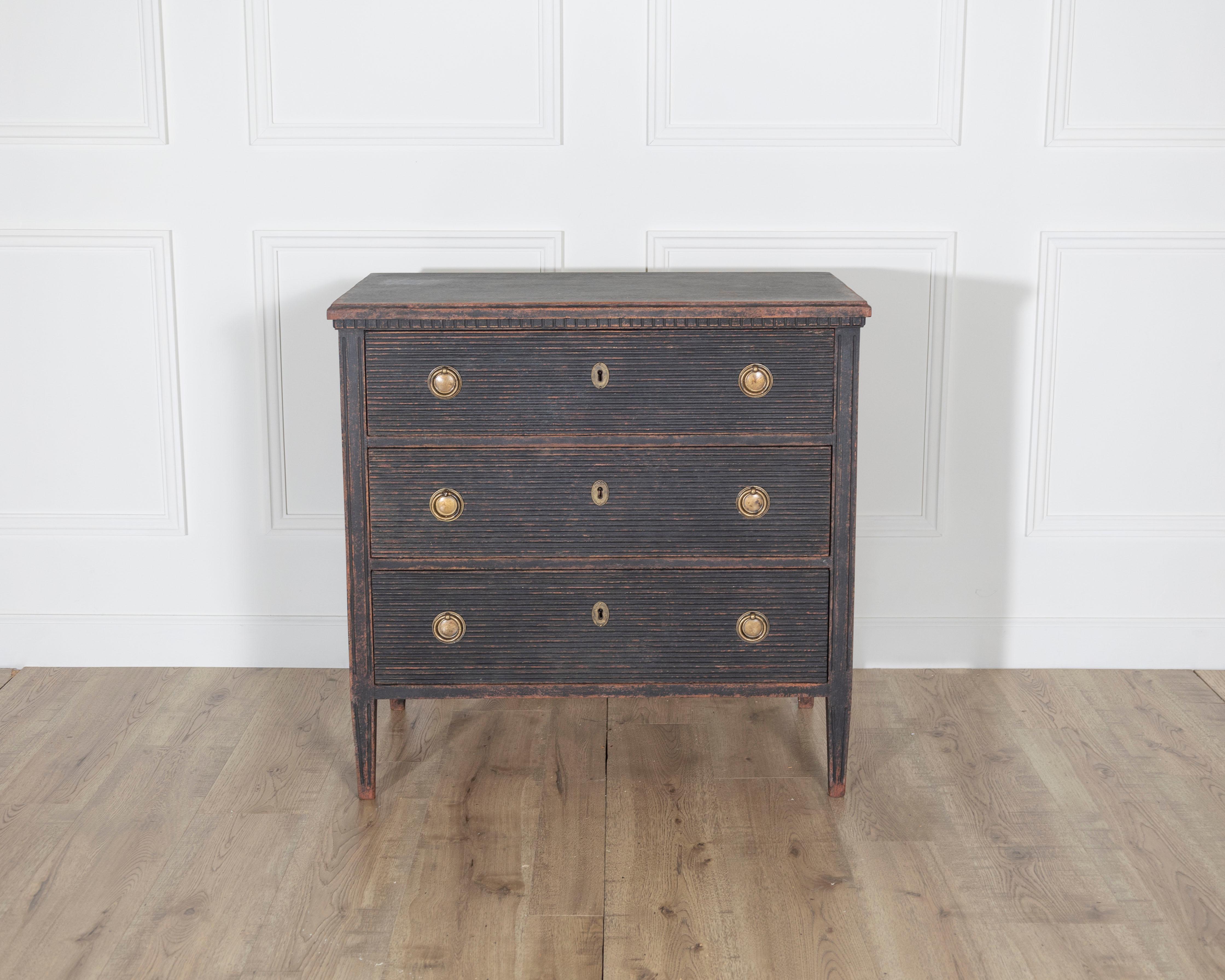 A beautifully crafted Gustavian style chest of drawers from Sweden, dating to circa 1900–1920. Finished in a deep black paint with a soft, timeworn patina, this chest balances neoclassical elegance with rustic charm. The three drawers are adorned