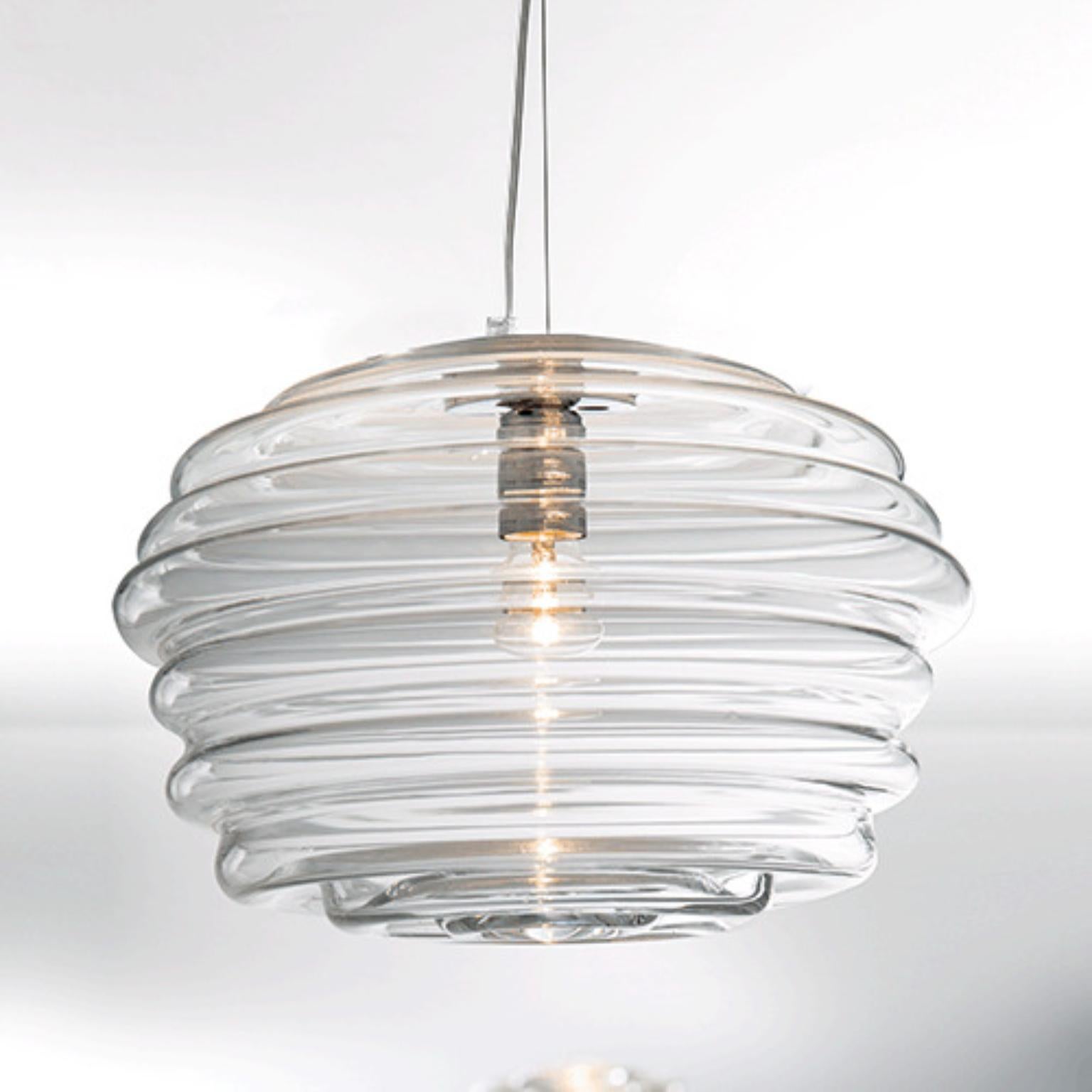 Lampada a sospensione Onda ONDSOMBG di Mazzega 1946
Dimensioni: D 42 x H 150 cm.
Materiali: Telaio: Cromo lucido.
Diffusore: Cristallo trasparente.
Peso: 5,5 kg. 

Gettando un sasso nel lago, le onde si propagano naturalmente dal centro formando