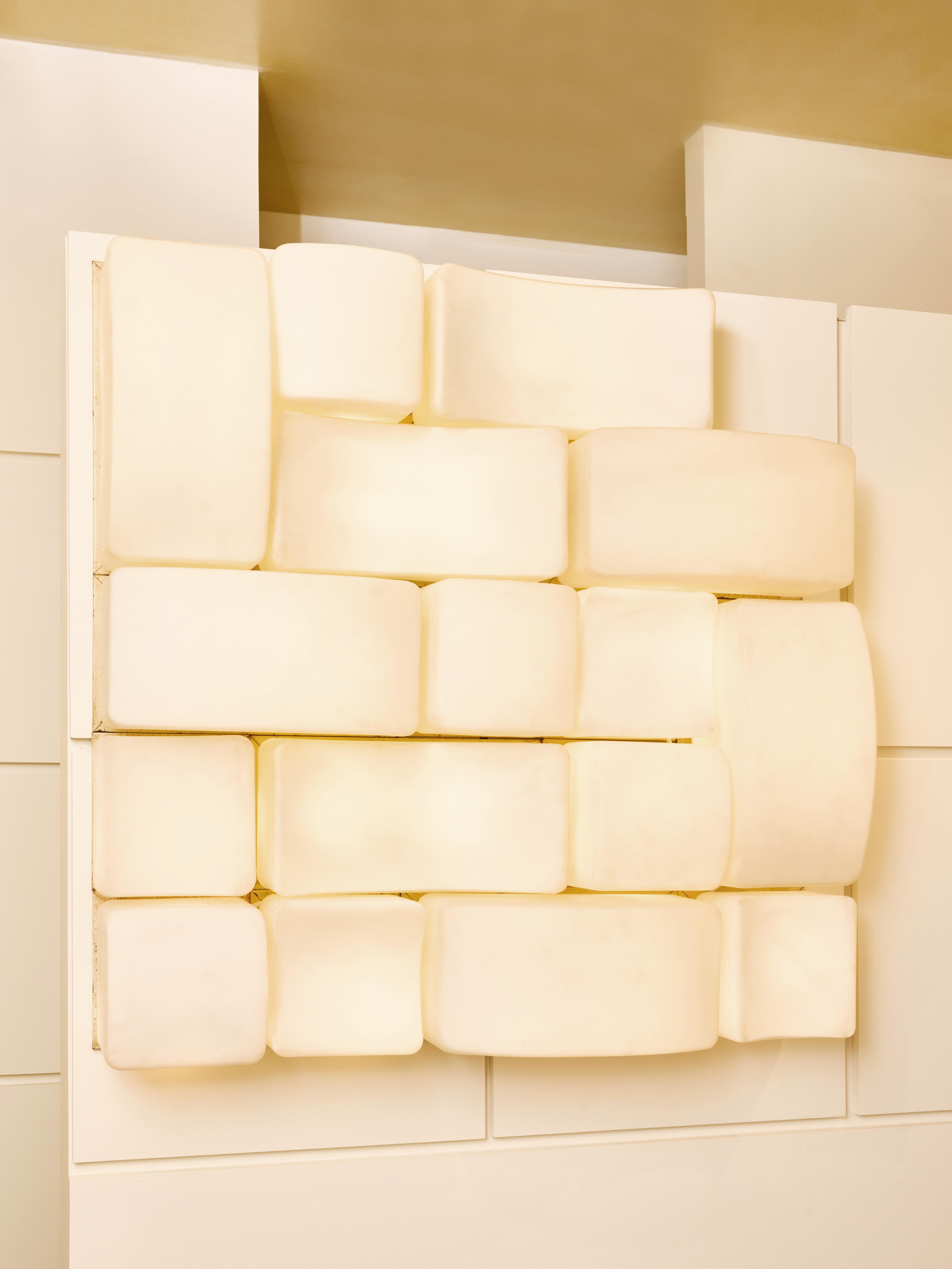 Large set of Onda wall sconces designed by Claude Salocchi for Lumenform in the 1960s.
These sconces, available in four distinct variations, feature a metal backplate onto which a brick-shaped opaline glass diffuser is affixed. They come in two