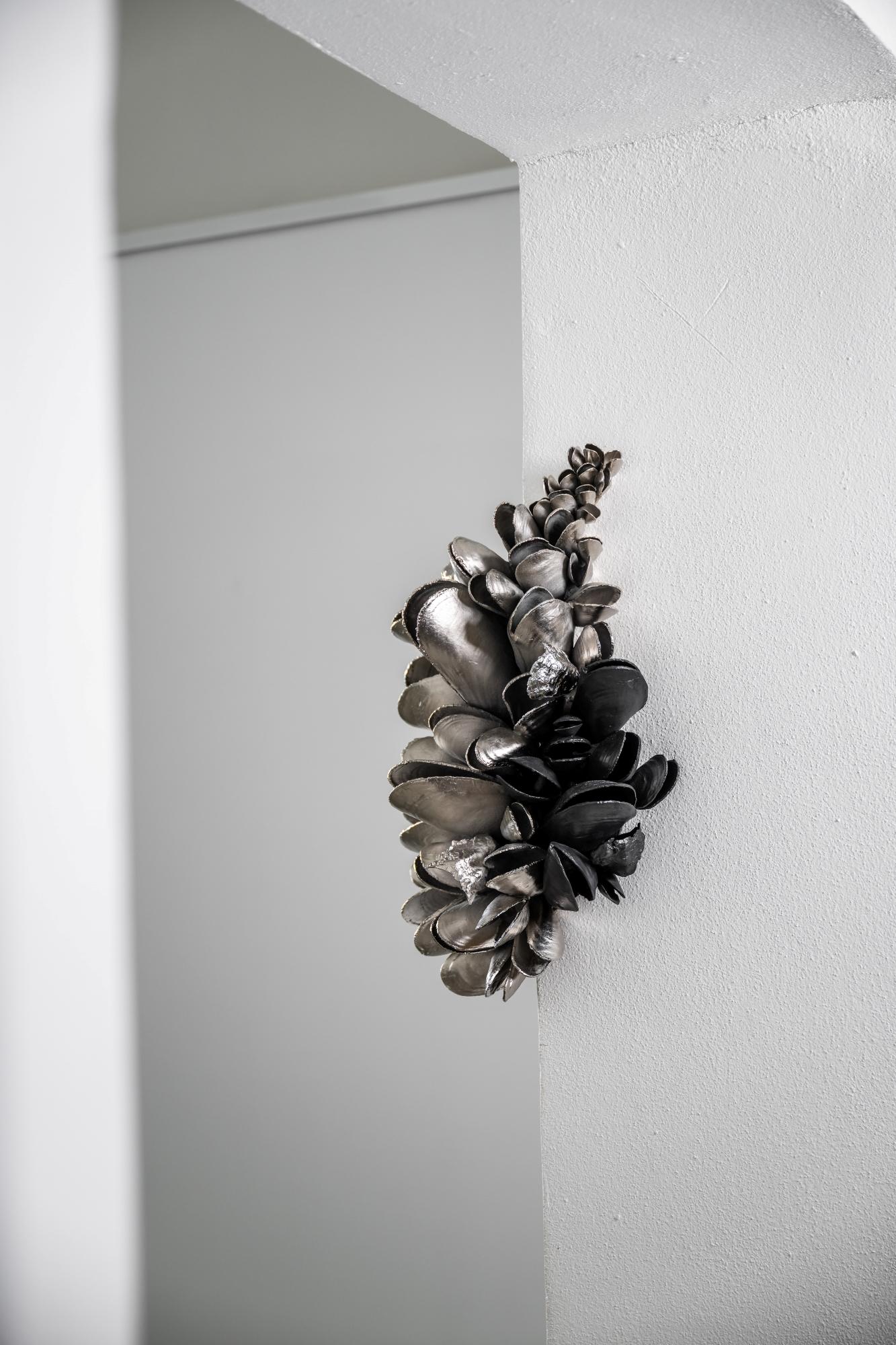Instant Moules V è una scultura da parete in alluminio nichelato ed elox dello scultore ceco contemporaneo Ondřej Oliva. Le dimensioni sono 50×35×25 cm.
Le conchiglie dei molluschi sono disposte ad arte su un bouquet. Questa opera d'arte unica è