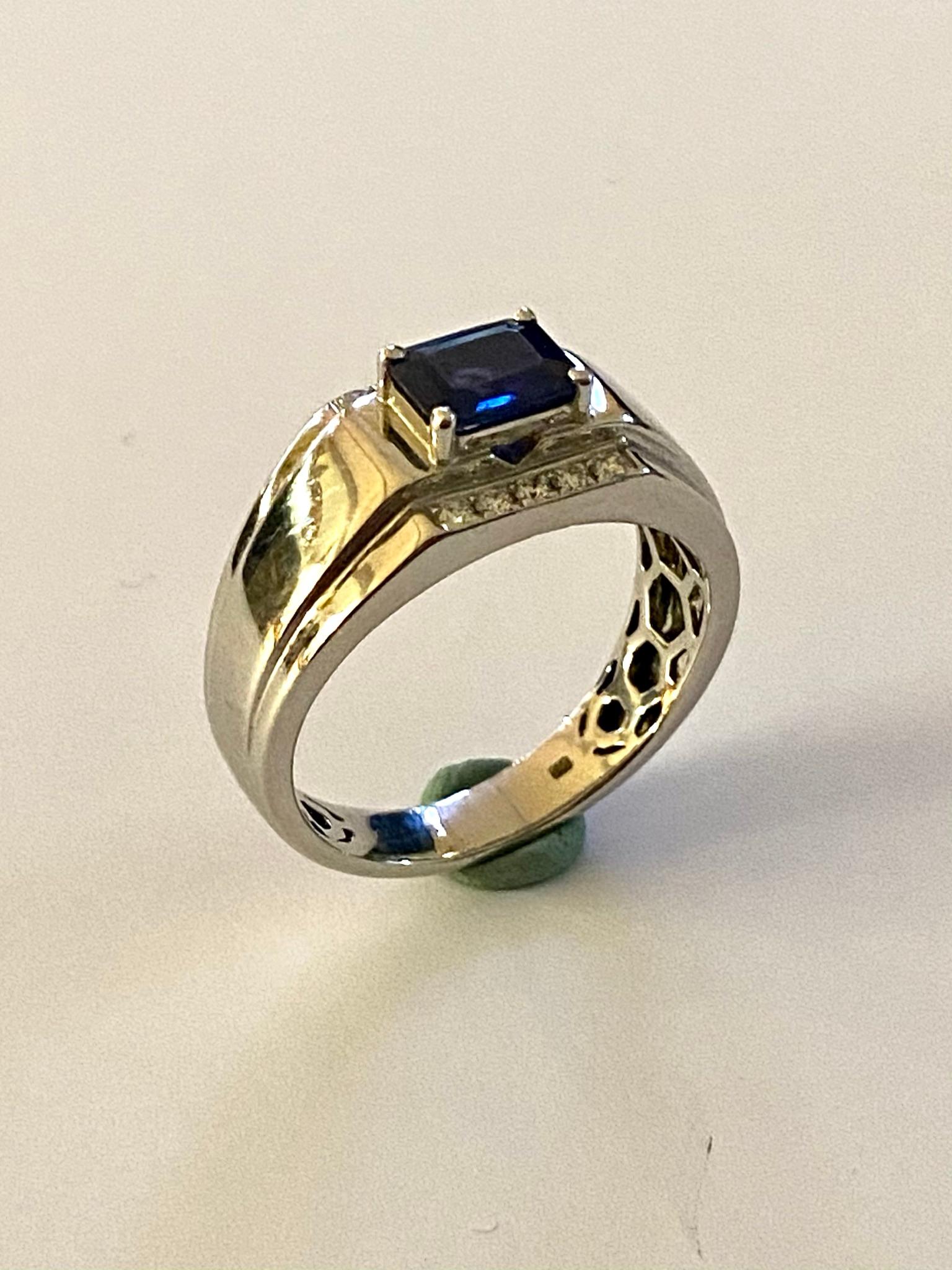 One (1) 18k. White Gold Sapphire & Diamond Ring.
1 Natural Corundum, Sapphire, Emerald, step cut  = 6.6 x 5.3 x 2.7 mm  = 1.00 Carat  (indications of heating present)
10 natural Diamonds, round Brillilant = 0.15 ct (total)  VSI - SI  F-G
Total