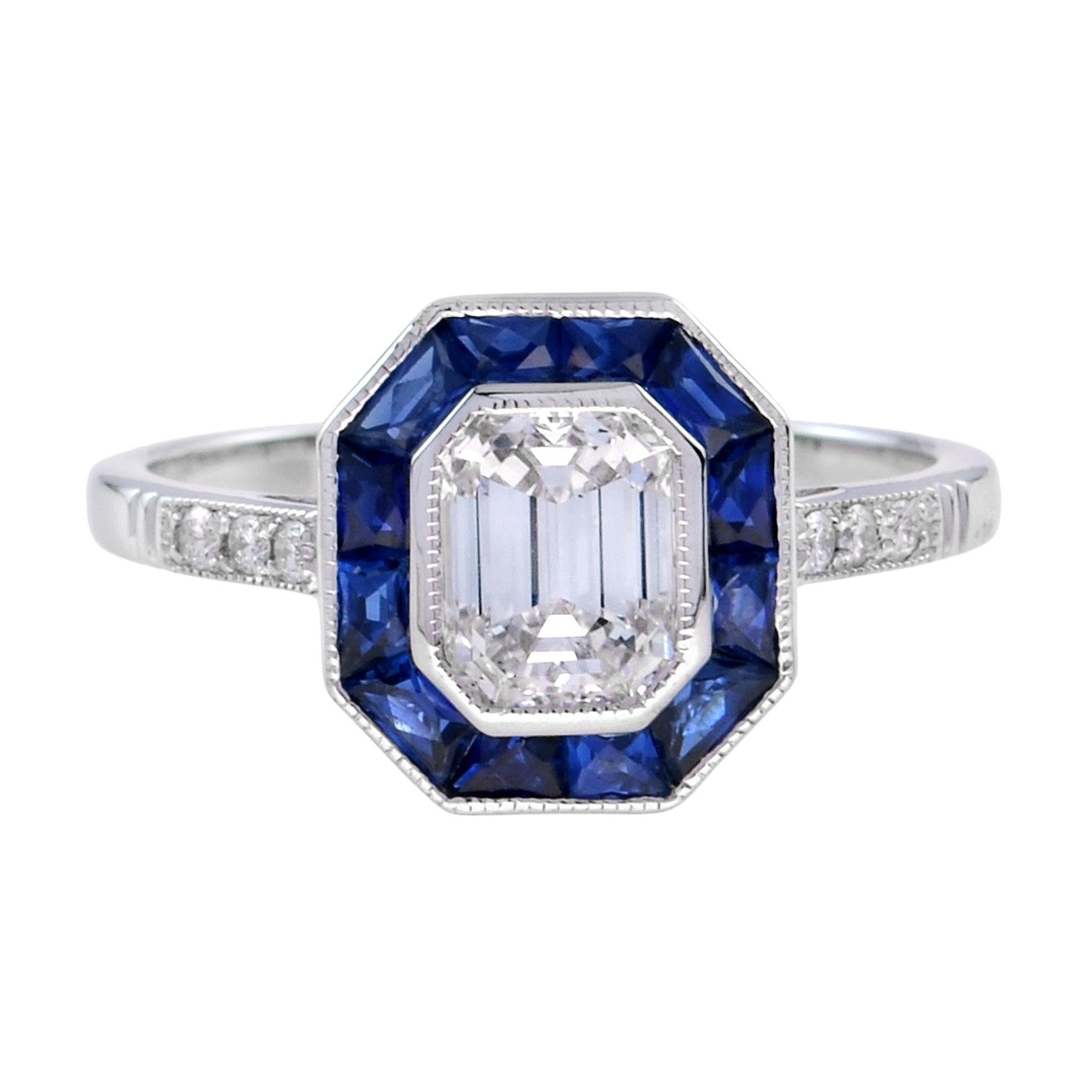 A stunning diamond and sapphire ring, centered with a beautiful emerald cut GIA certified diamond setting surrounded by a fine geometric frame of French cut sapphires and with diamond set shoulders, all in a finely hand-crafted 18K white gold mount