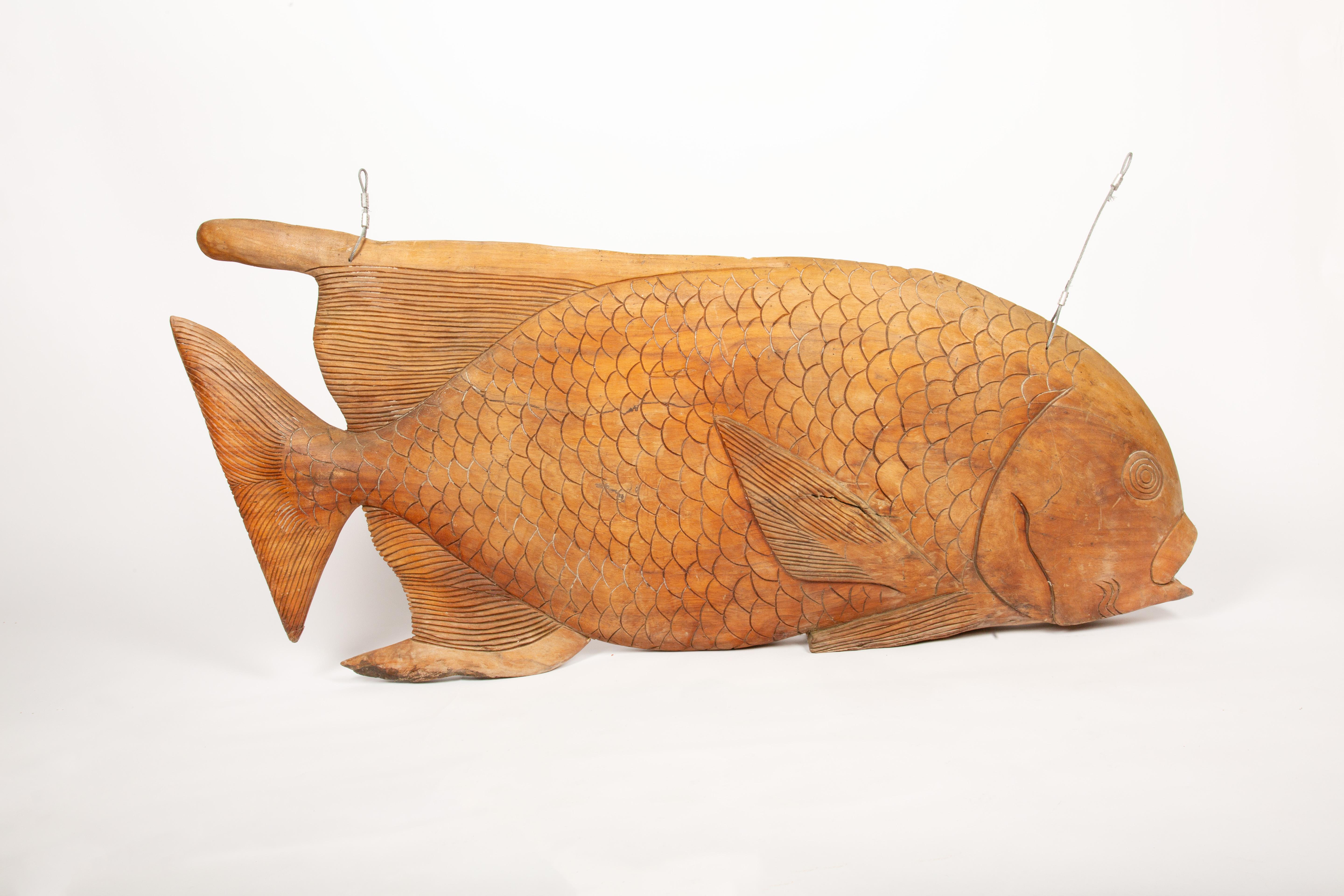 Cet énorme panneau commercial en bois sculpté à la main est un exemple impressionnant d'artisanat et d'art populaire maritime. Sculptée dans une seule pièce de bois massif, elle mesure 50 pouces de large et présente des écailles méticuleusement