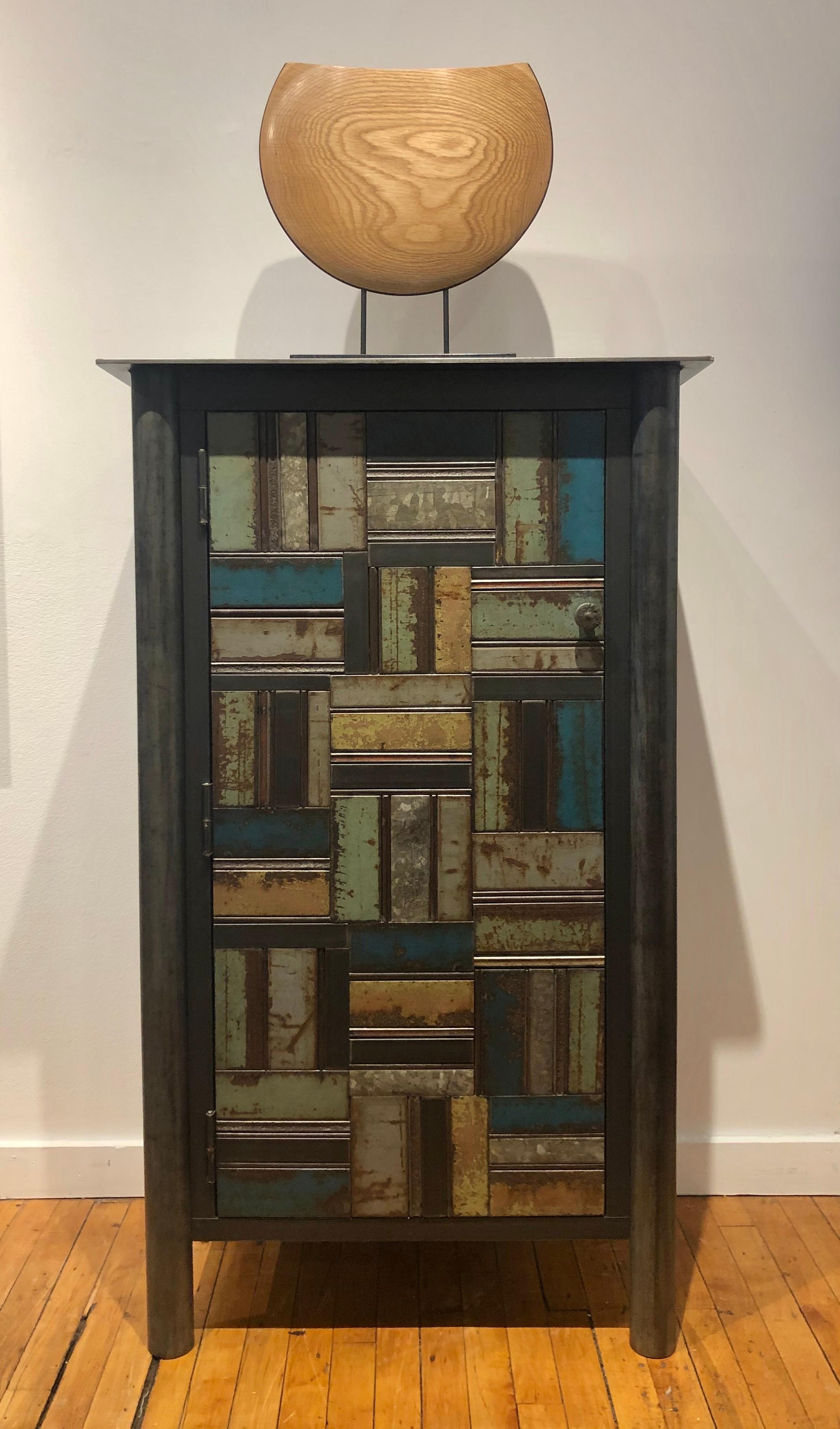 This is a totally functional one door cupboard. It is created from hot rolled steel and found steel. The legs are made from salvaged pipe. The panels on the door fronts and sides are made from salvaged pieces of steel with the original paint and