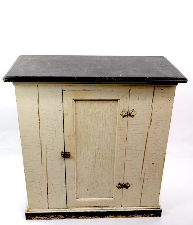 Nice antique American kitchen cabinet with one door, which opens to reveal shelved storage. Nice graphic white and black color way, original paint finish shows attractive alligatoring to surface. Oilcloth top shows some cosmetic wear, normal and